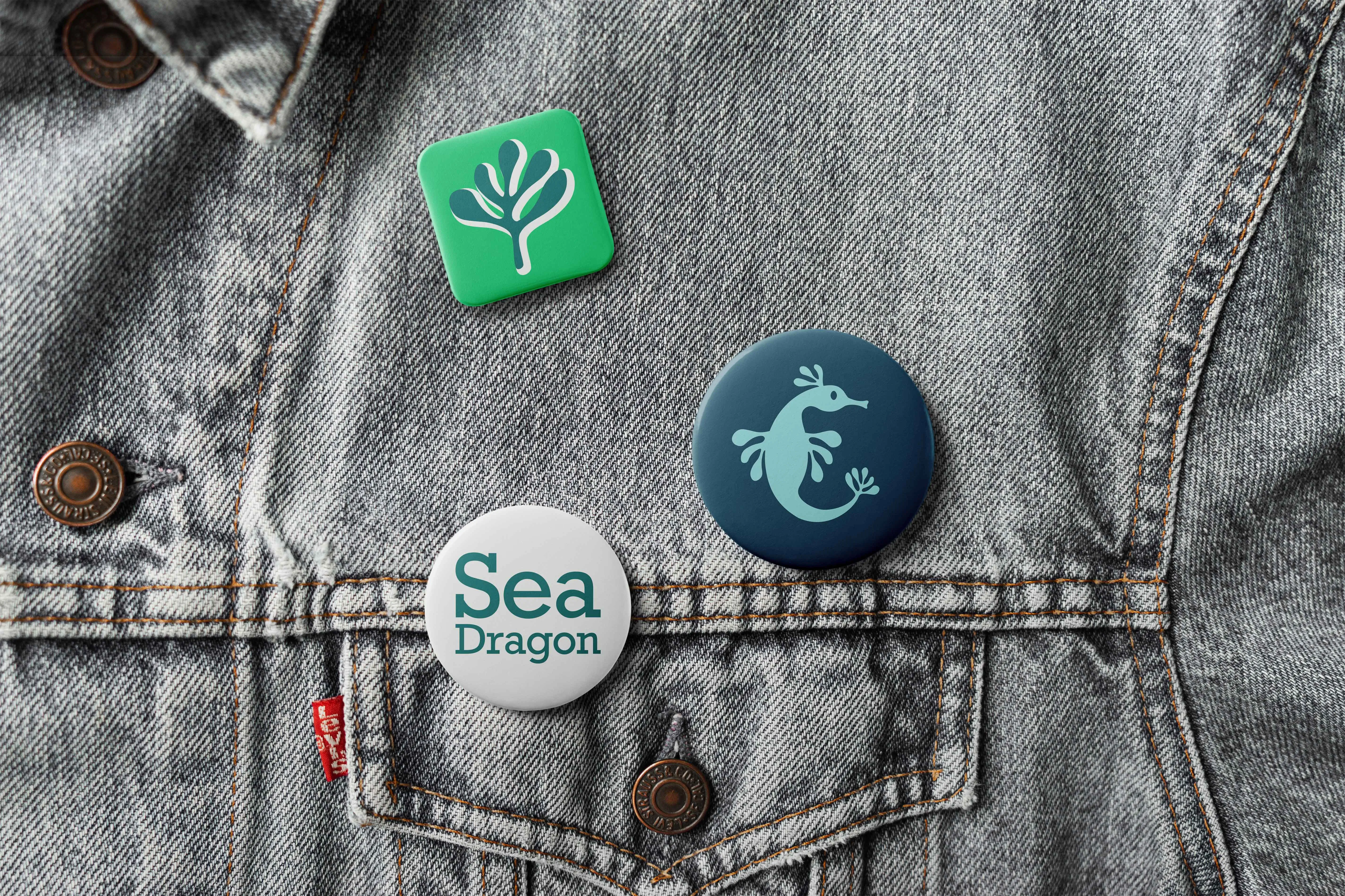 Close-up of denim fabric with three colorful buttons pinned to it, featuring various designs.