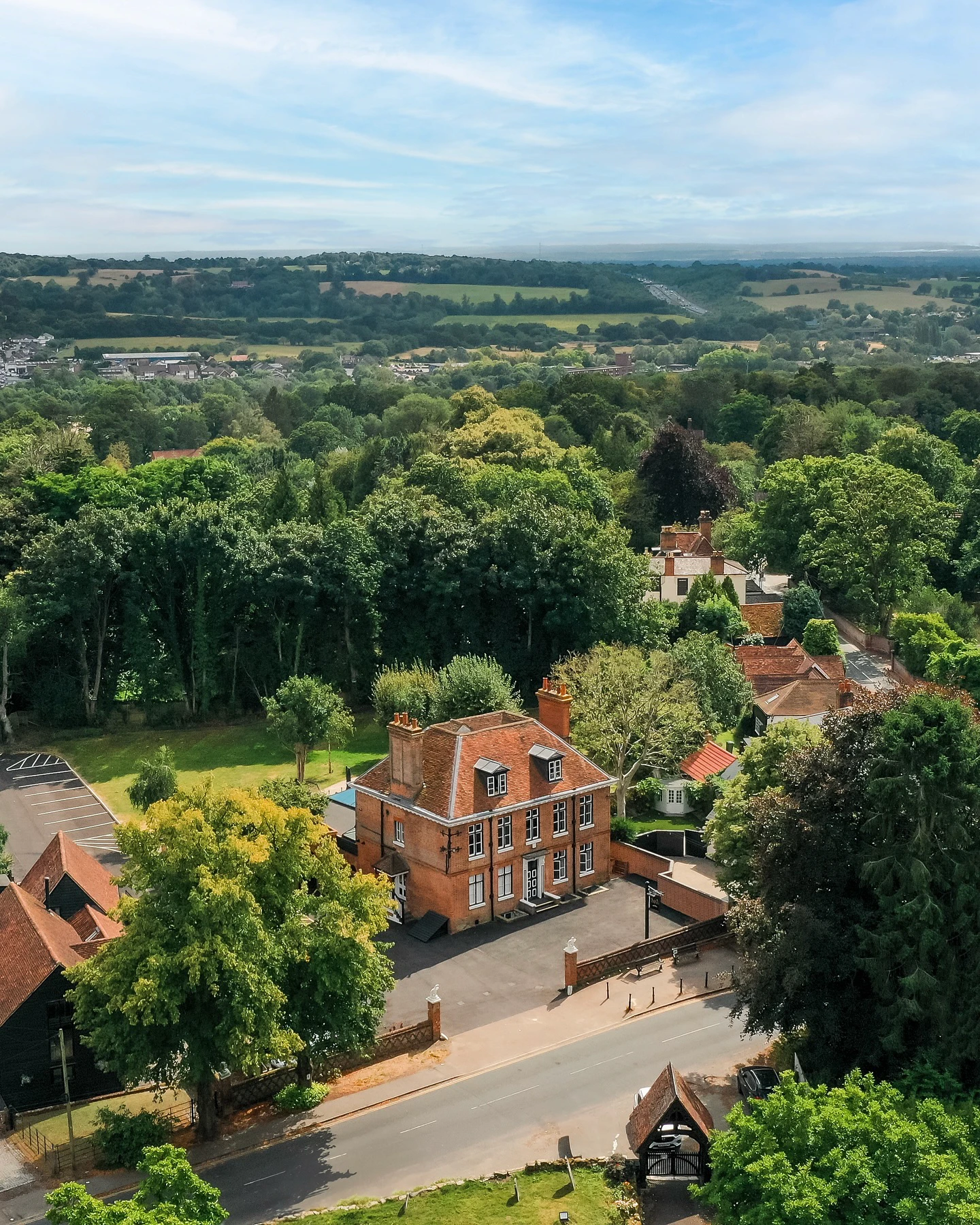 Aerial view of a brick manor house amongst trees