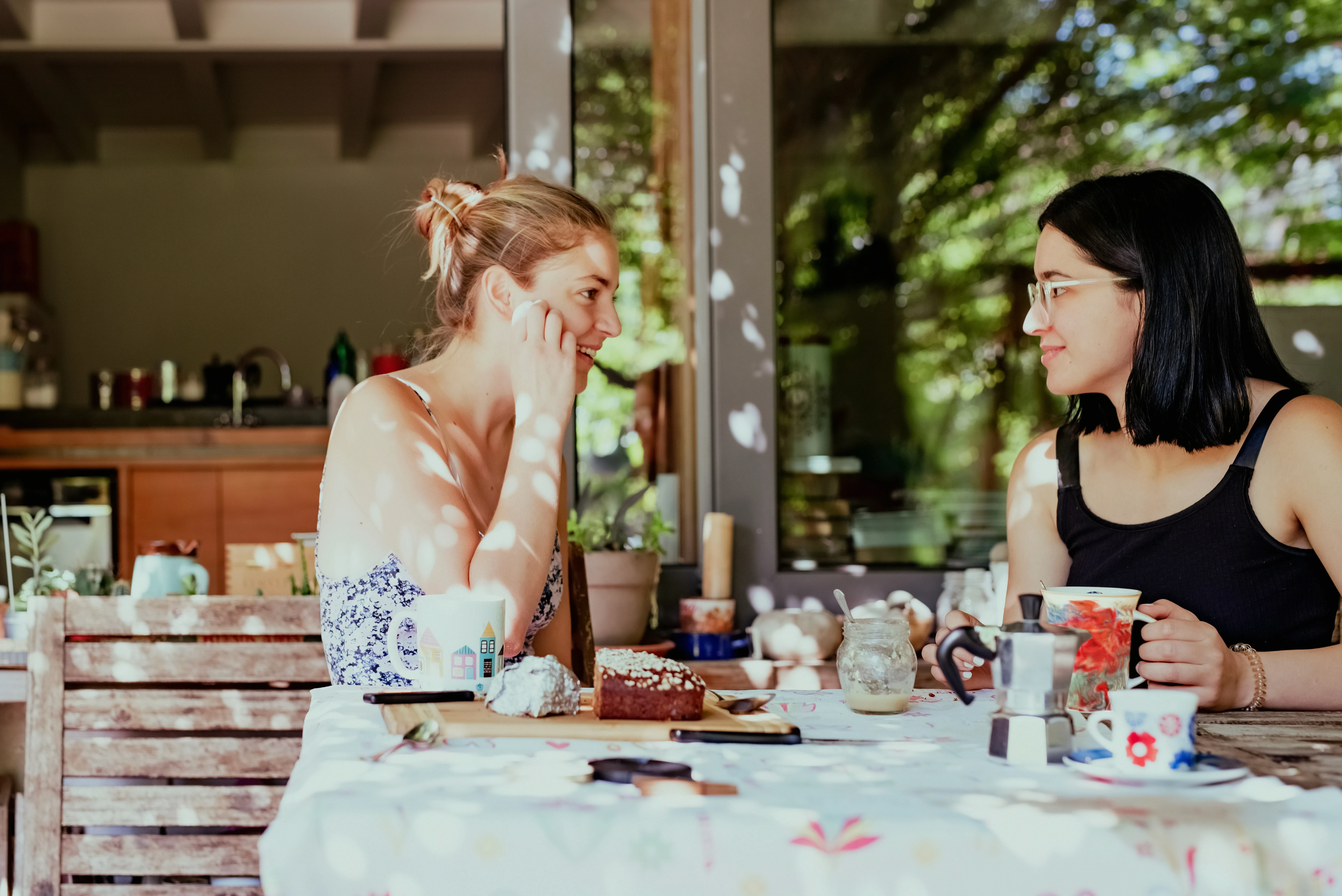 Two women having coffee and an engaged conversation at a table, representing friendship, connection, and social support.