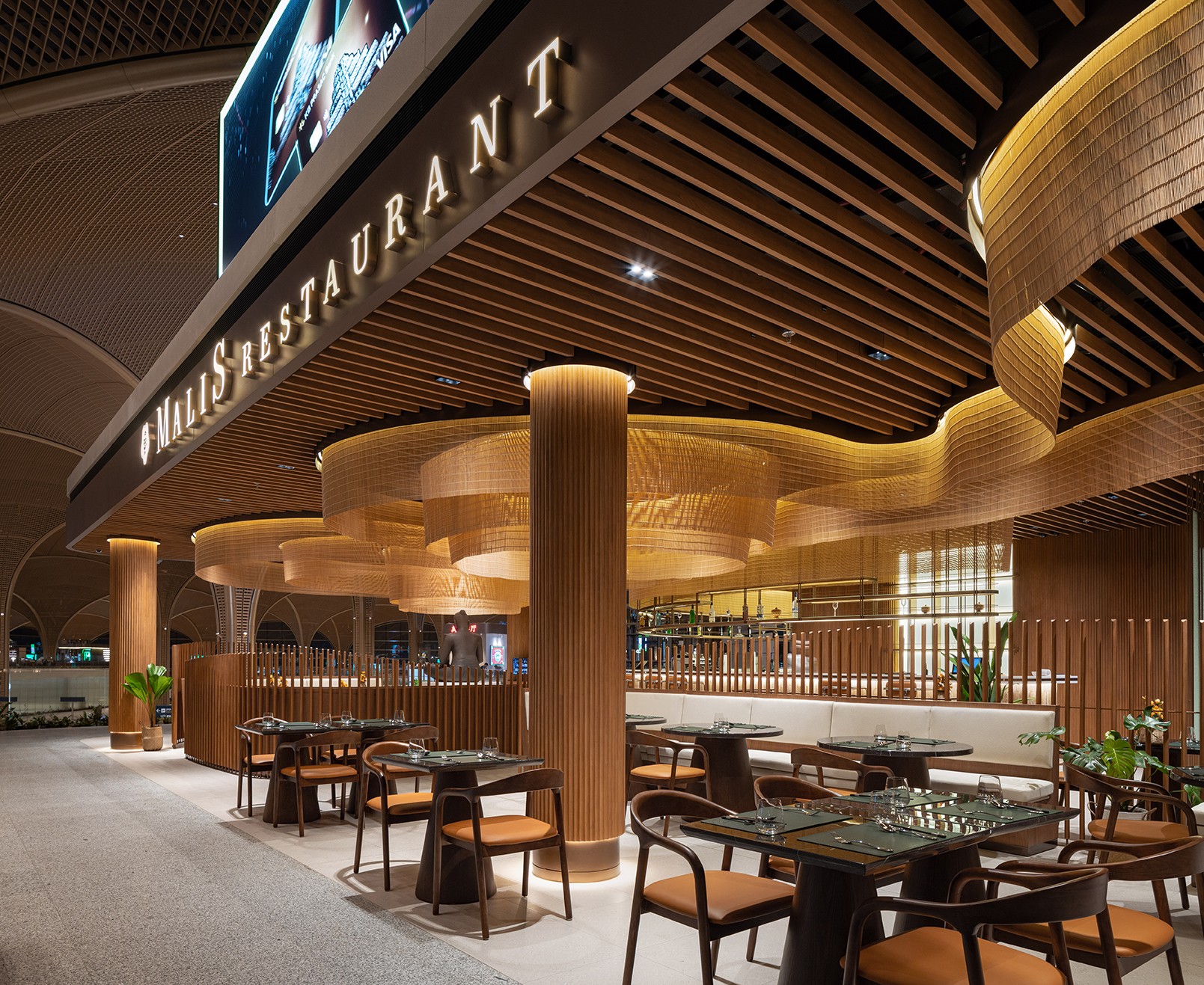 Entrance view showing the complex timber slat ceiling and integrated signage of Malis Restaurant reflecting the rigorous technical standards and documentation required for high-traffic public spaces