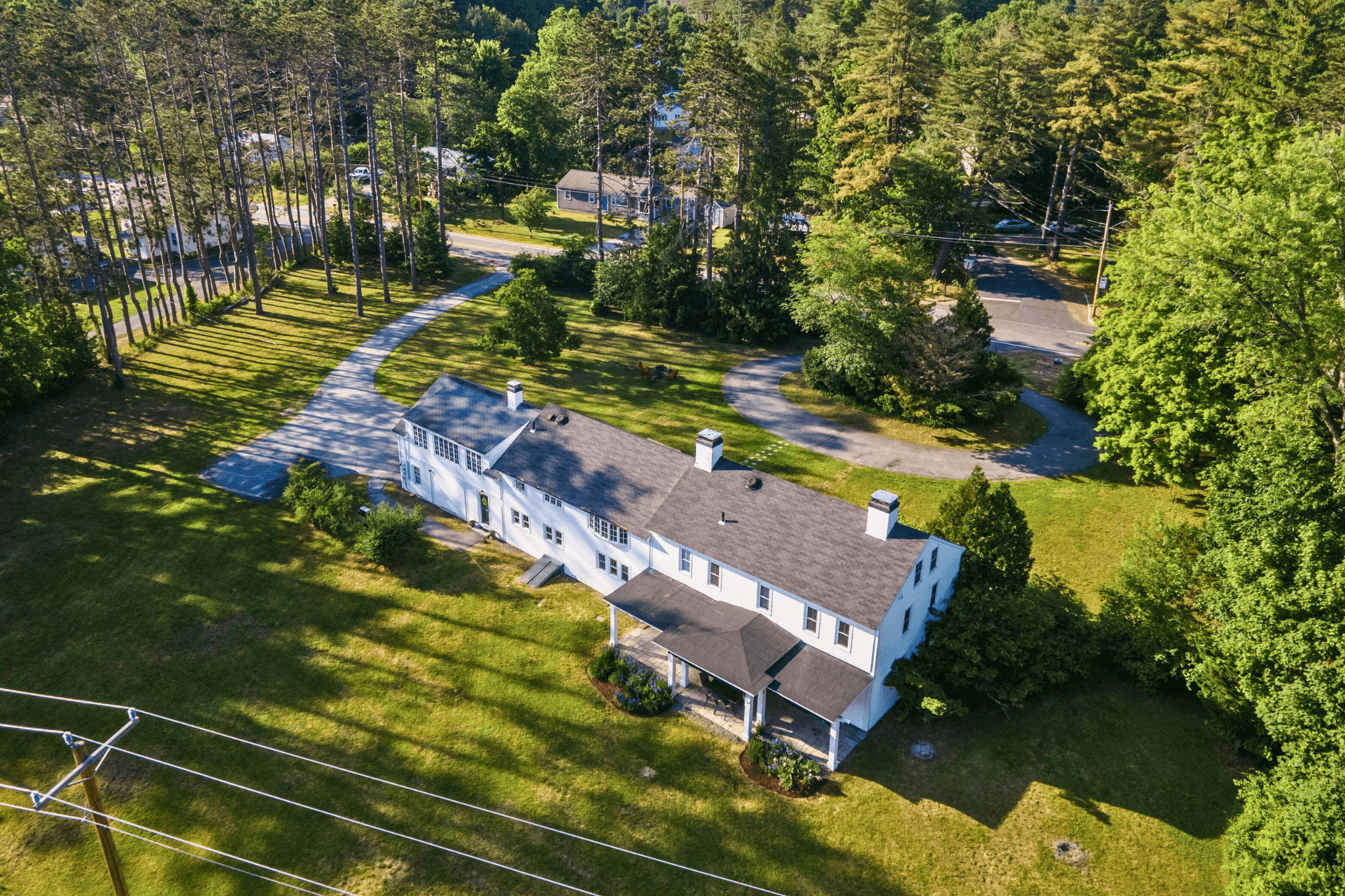 Aerial view of Four Winds Estate, a historic Concord, NH vacation rental on 5.5 acres, surrounded by tall pines and expansive lawns—listed in the top 5% of homes on Airbnb.