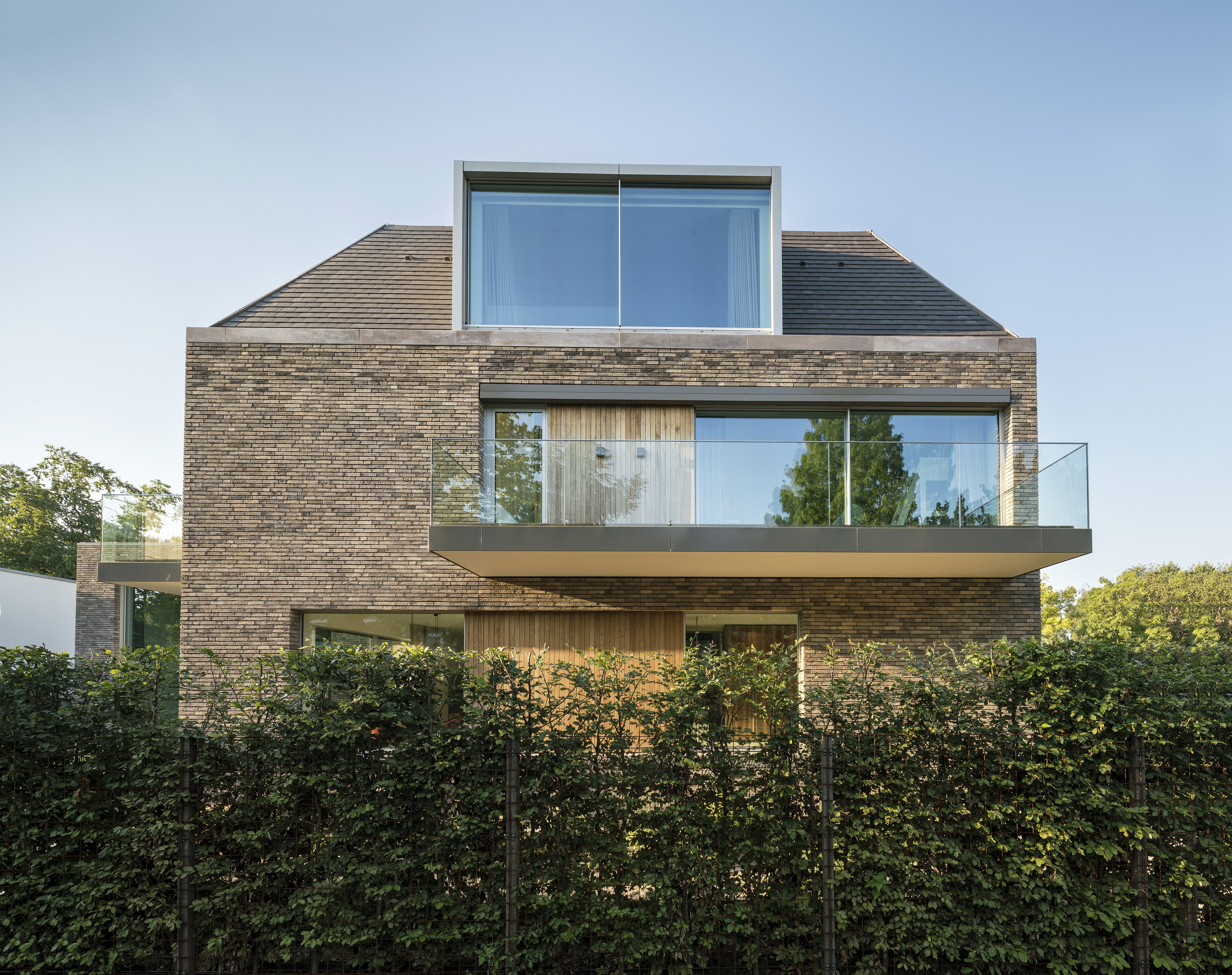 Modern huis met bakstenen gevel, balkon en groot raam op het dak.