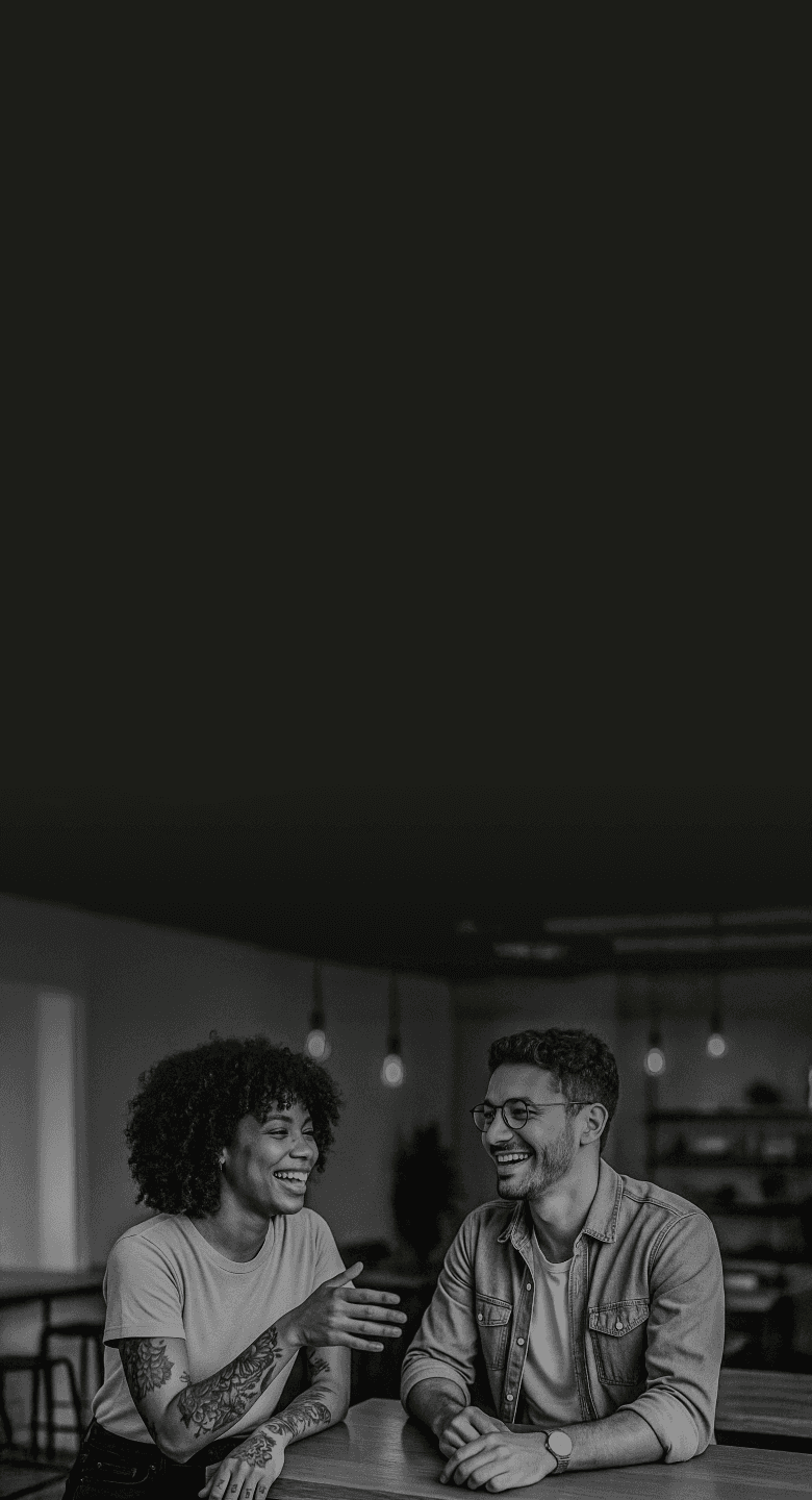 Casal de empreendedores da economia criativa em ambiente moderno e acolhedor, sorrindo em momento de colaboração