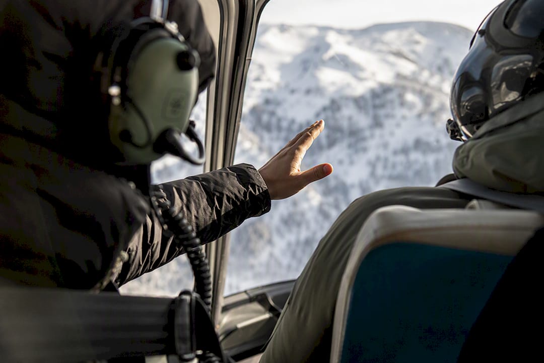 Helicopter passenger wearing a headset and raising a hand inside the cabin