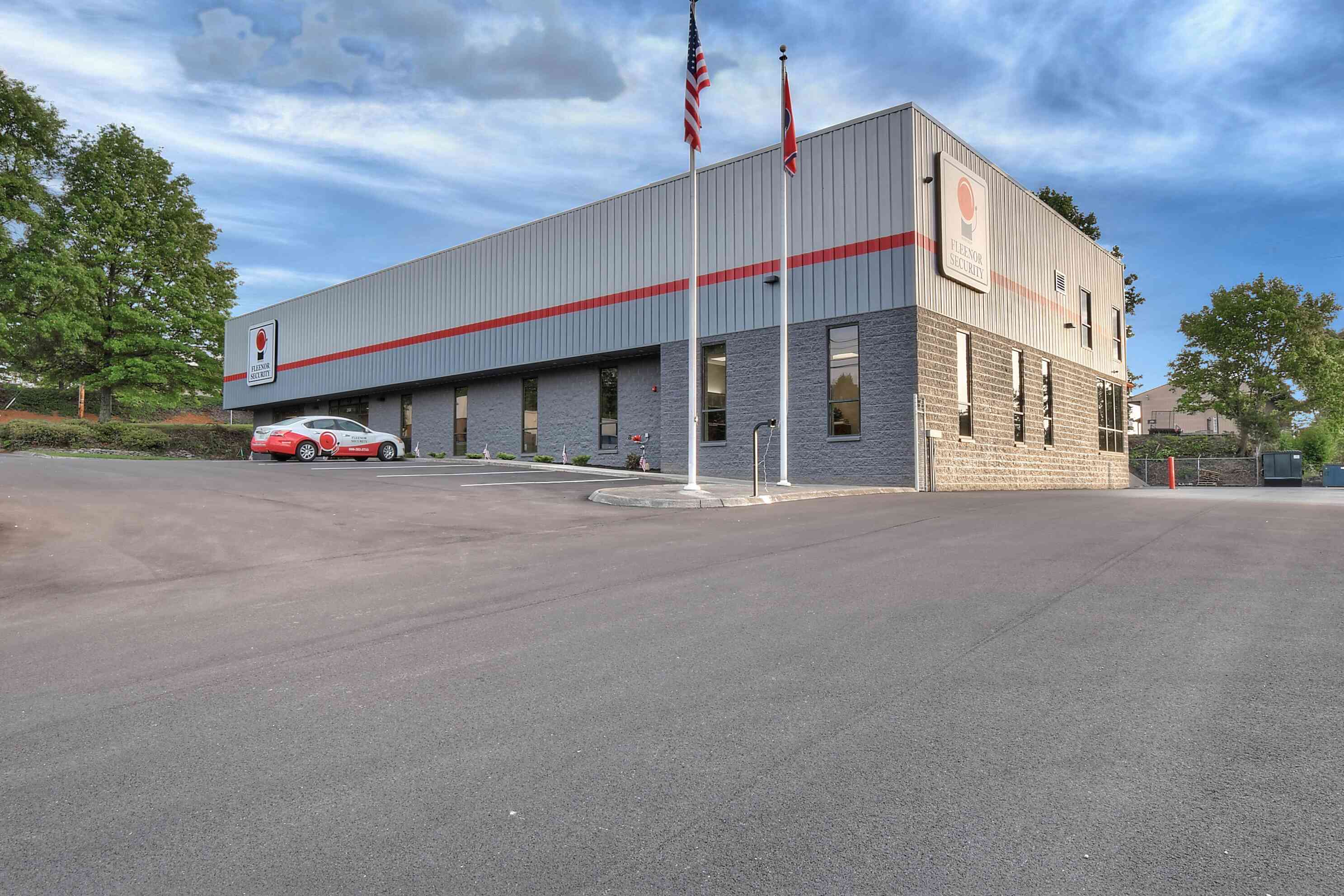A modern, building with a smooth exterior, surrounded by parking and trees under a blue sky.