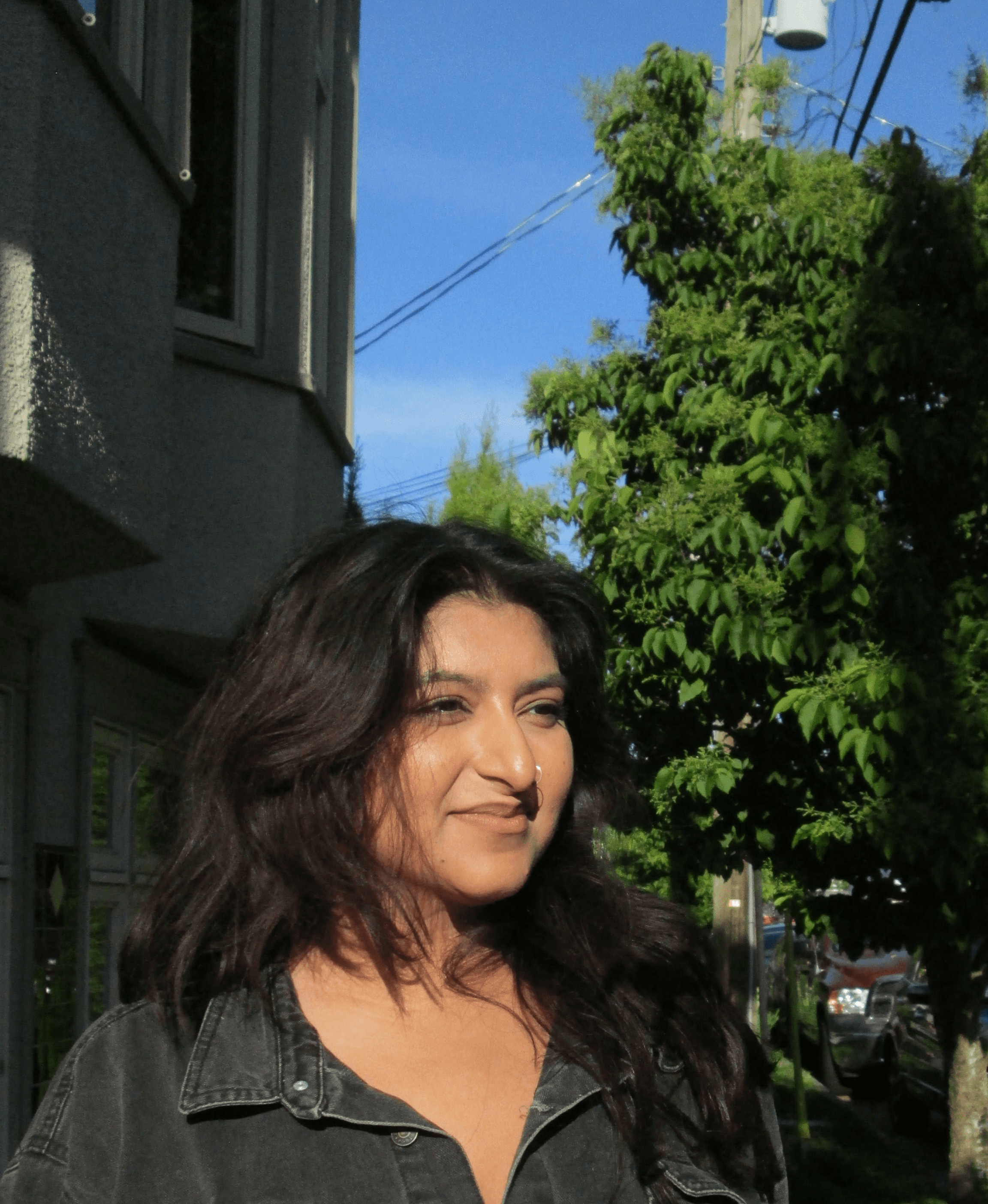 A thoughtful young person with dark hair gazes to the side, captured in soft black and white lighting.