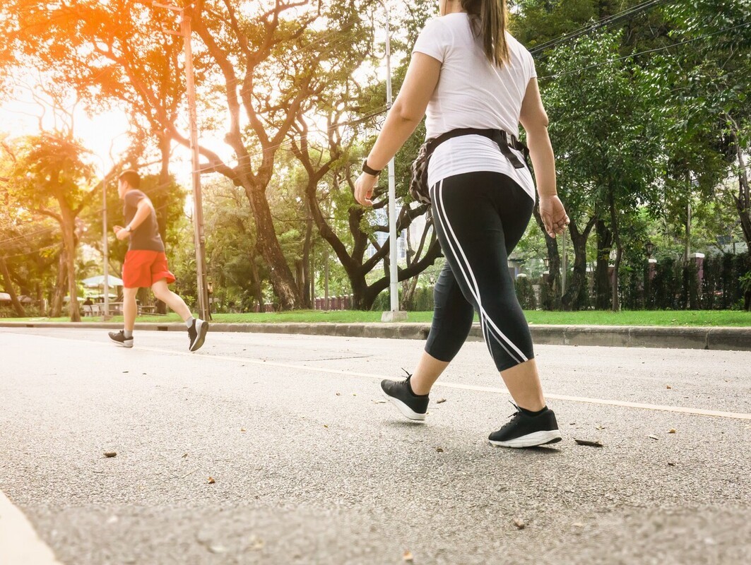 woman following her walking plan to lose weight by taking a 20-minute walk outside down the road