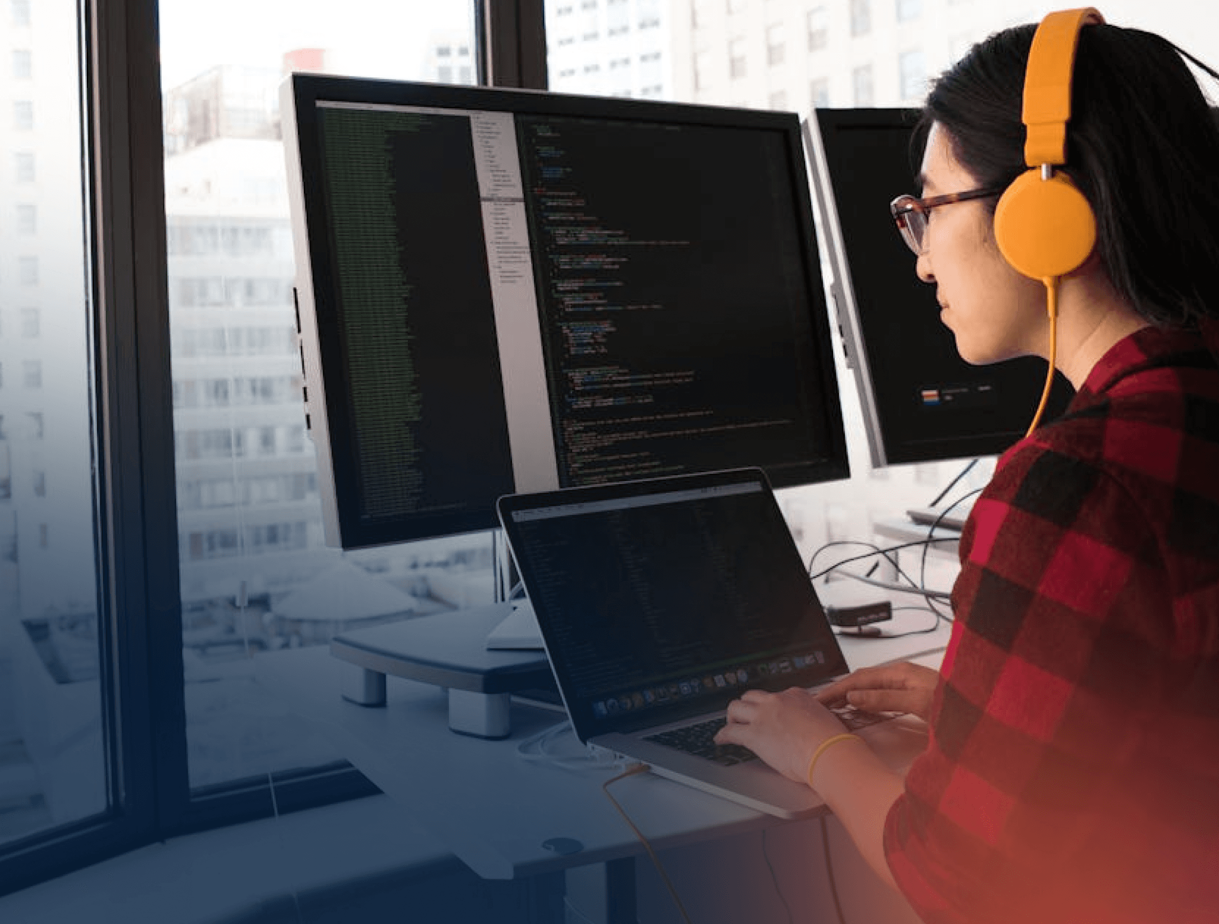 woman with headphones working on multiple screens