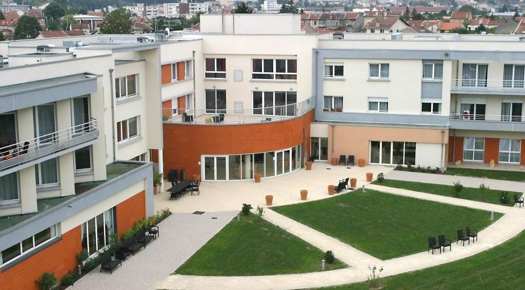 Contemporary residence building with red brick facade multiple floors and landscaped entrance area