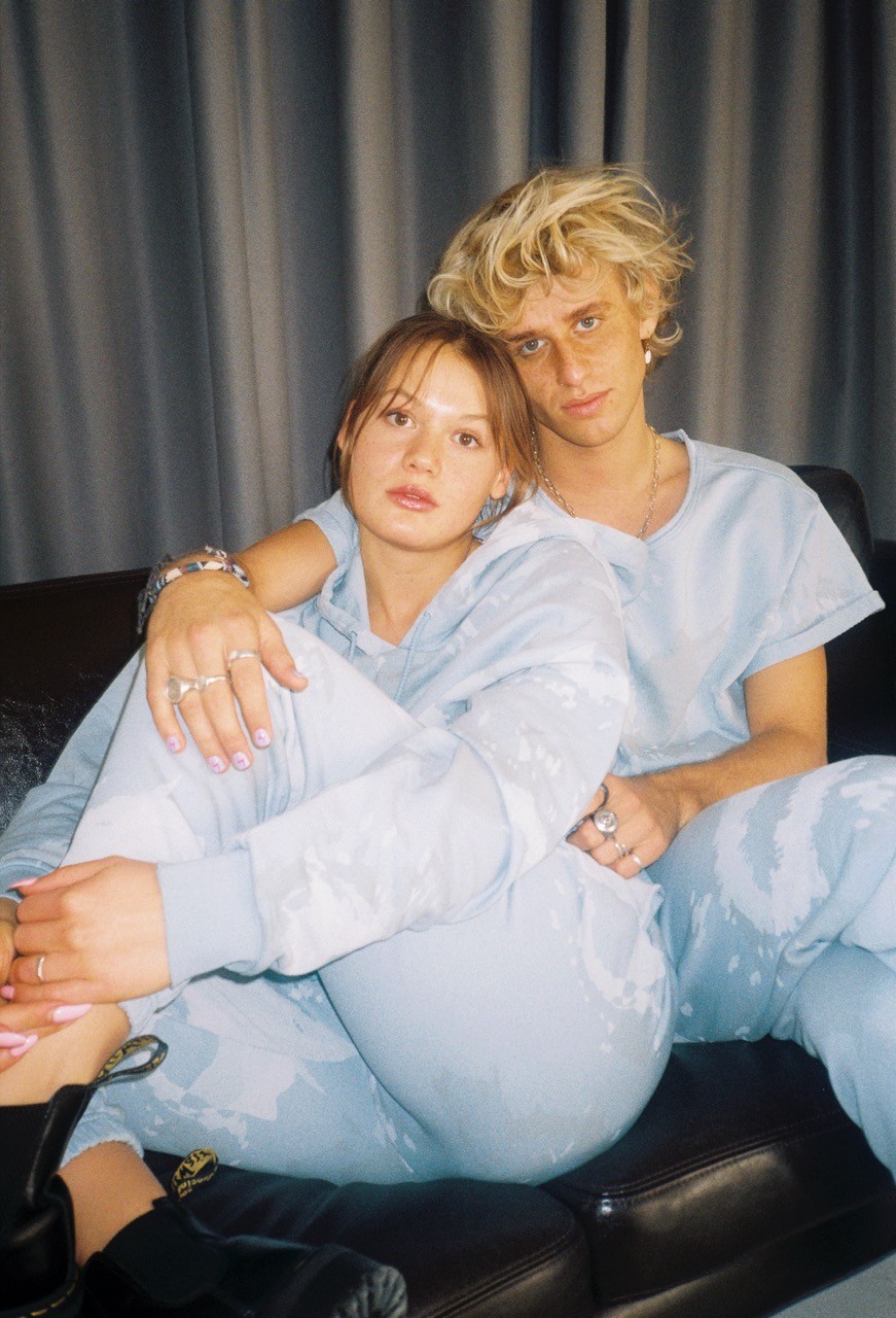 Theo Carow and model sitting on a couch in Catching Theo clothes