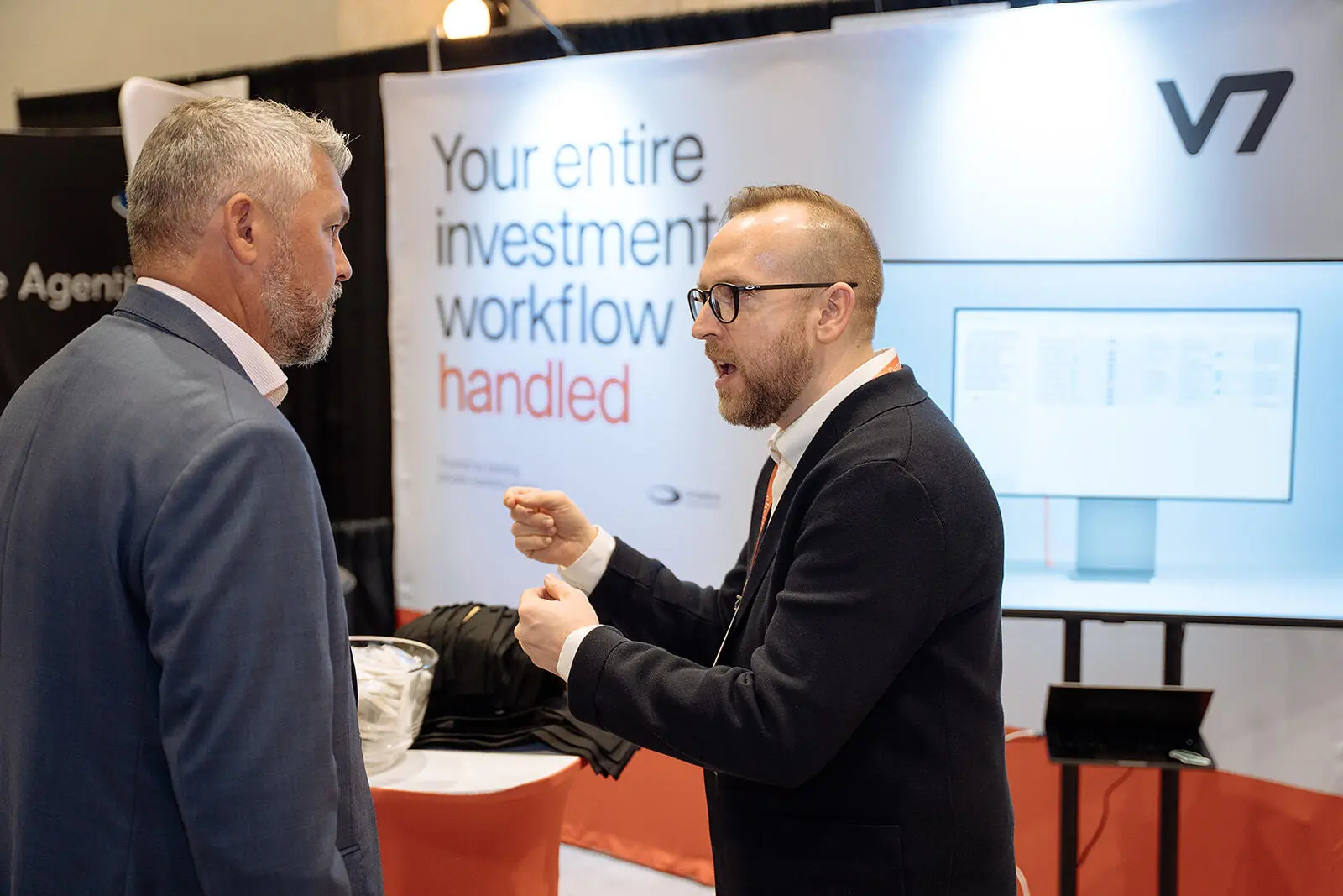 V7 team member talking with a visitor at the V7 booth at InvestOps USA 2026