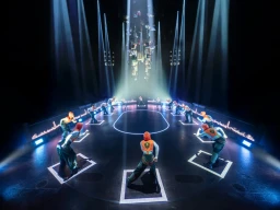 런던에서 막을 올린 연극 <헝거 게임> 무대 위, 빛나는 중앙 지점을 중심으로 각 구역의 조공인들이 박스 안에 배치되어 있습니다.