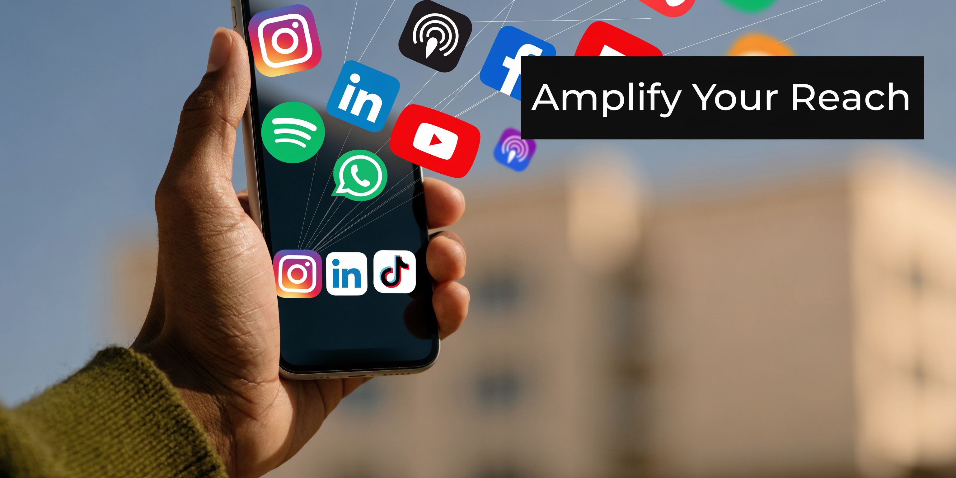 A hand holding a smartphone showing various social media application icons, symbolizing digital marketing and online reach.