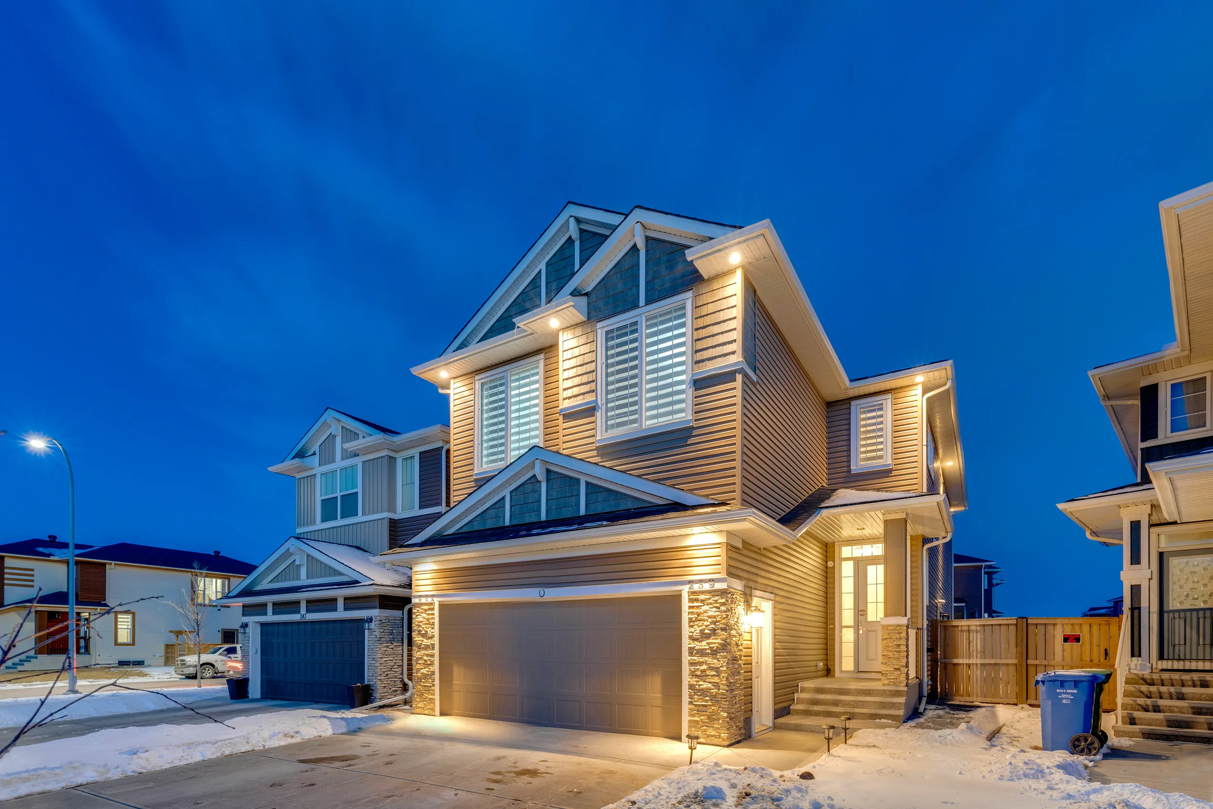 Craftsman-style home exterior with front porch and landscaped garden at dusk