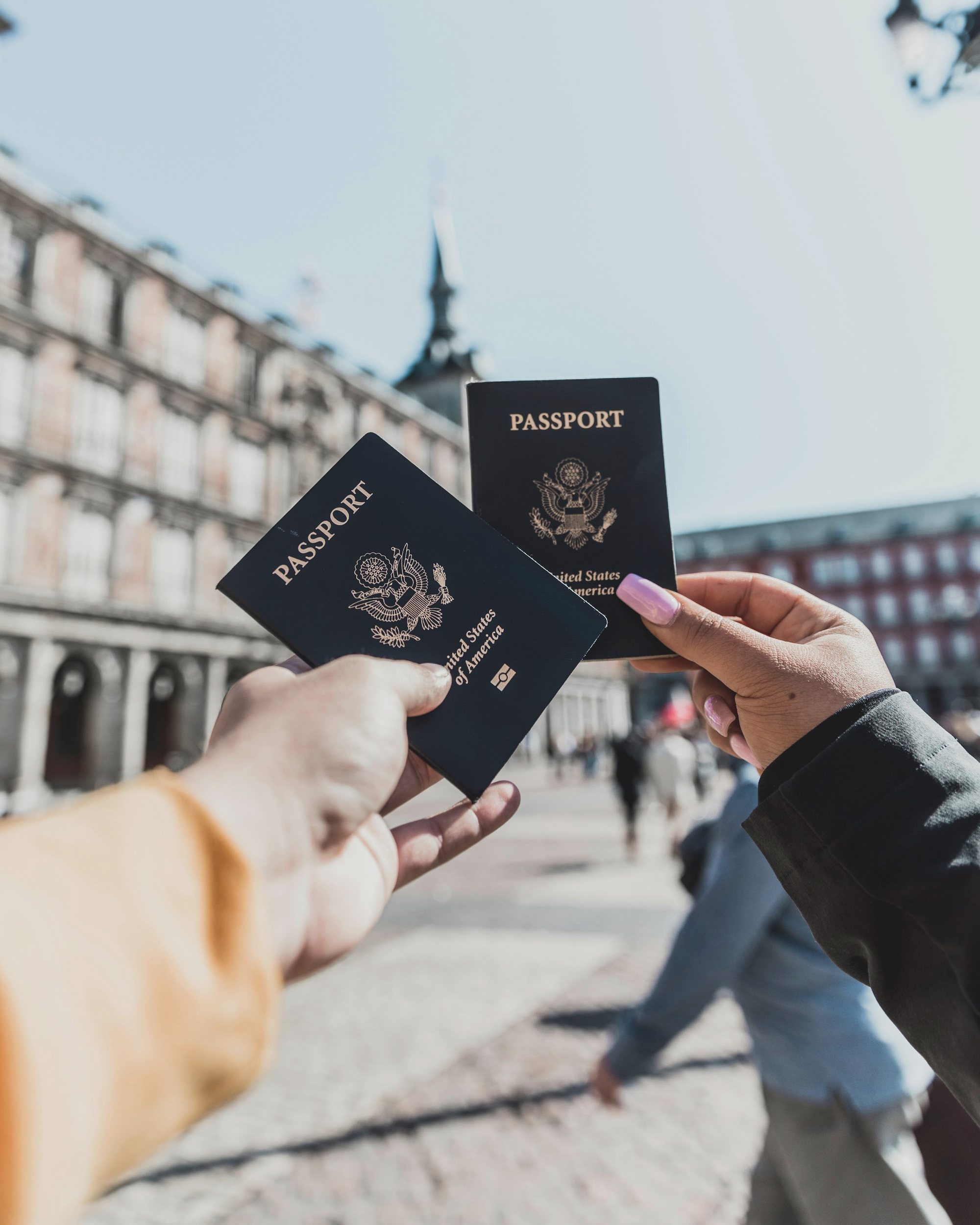Two passports held up in front of the Plaza Mayor in Madrid
