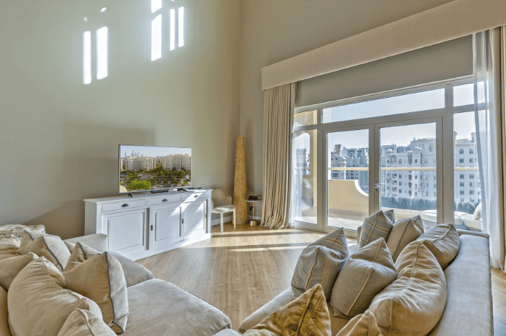 Interior of Shoreline Apartments' living room with a couch, a television, and stairs visible in the background.