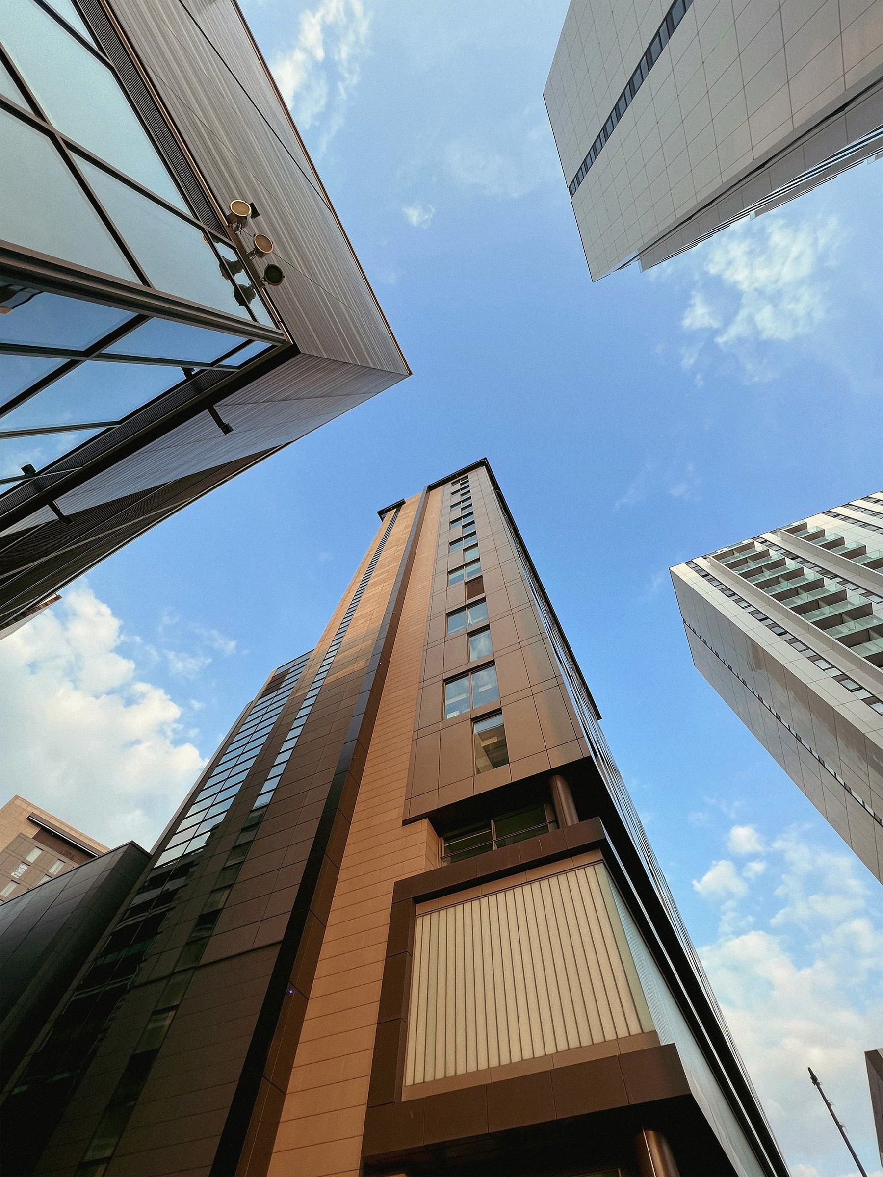 High-rise building with brown and beige exterior, viewed from below.