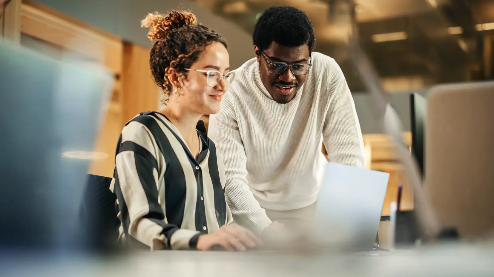 Two business colleagues collaborating at a laptop in an office, illustrating the working partnership between client and service provider