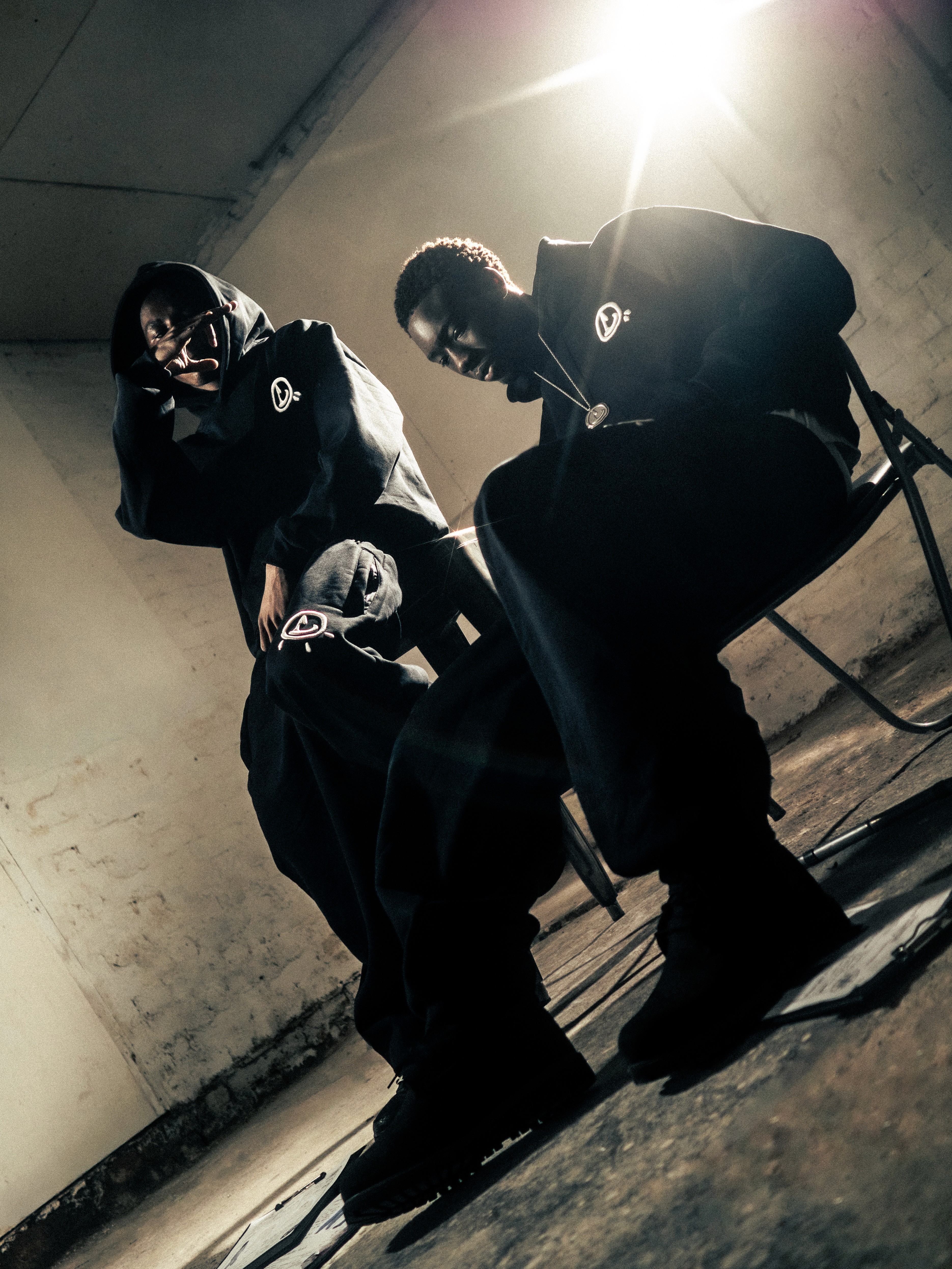 Man in a sporty jacket and light shorts walking across a football field, confidently pulling on his collar.