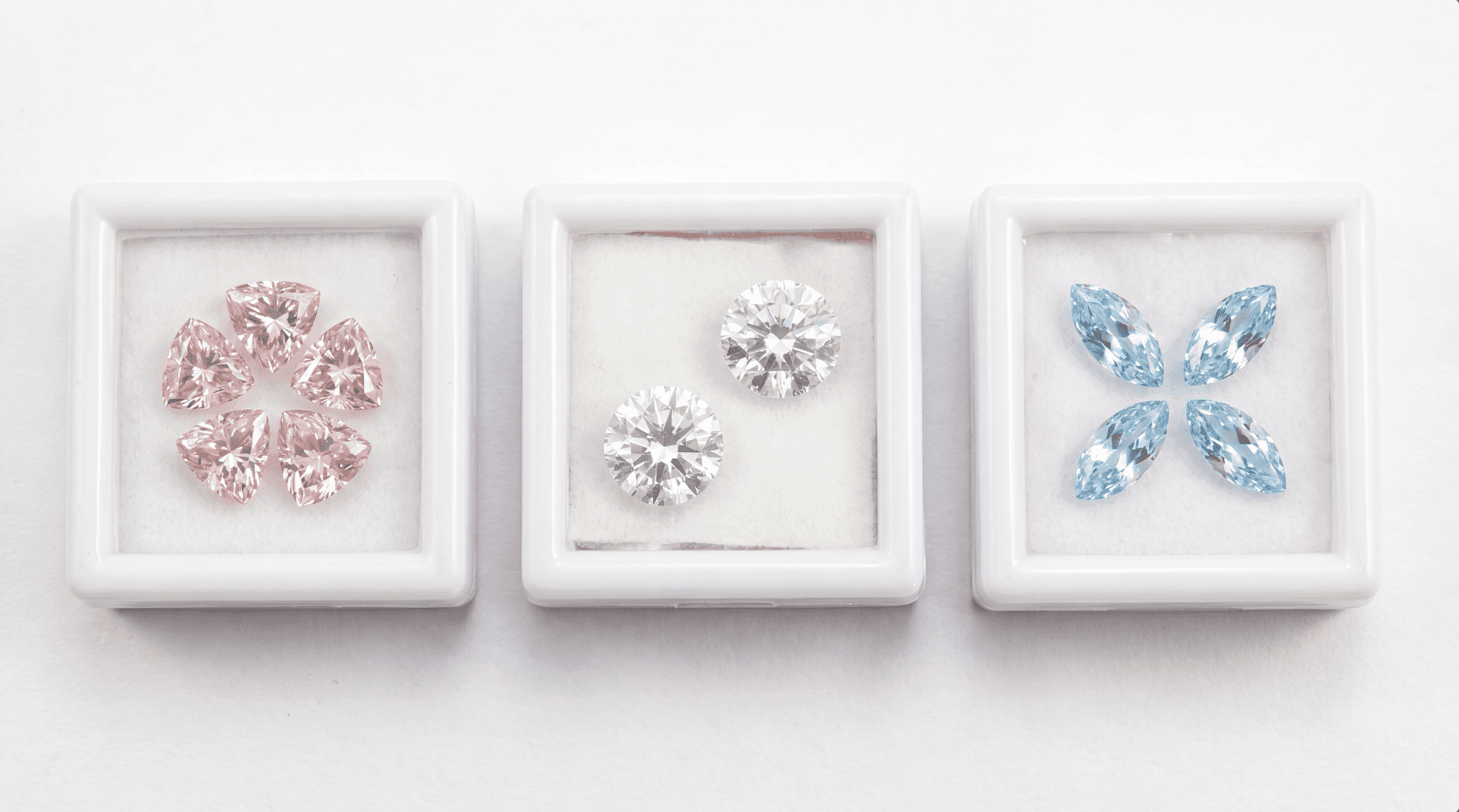 3 boxes of CVD diamonds, 5 trillion pink diamonds on the left box, 2 white round in the middle, and 4 marquise CVD diamonds on the right box.