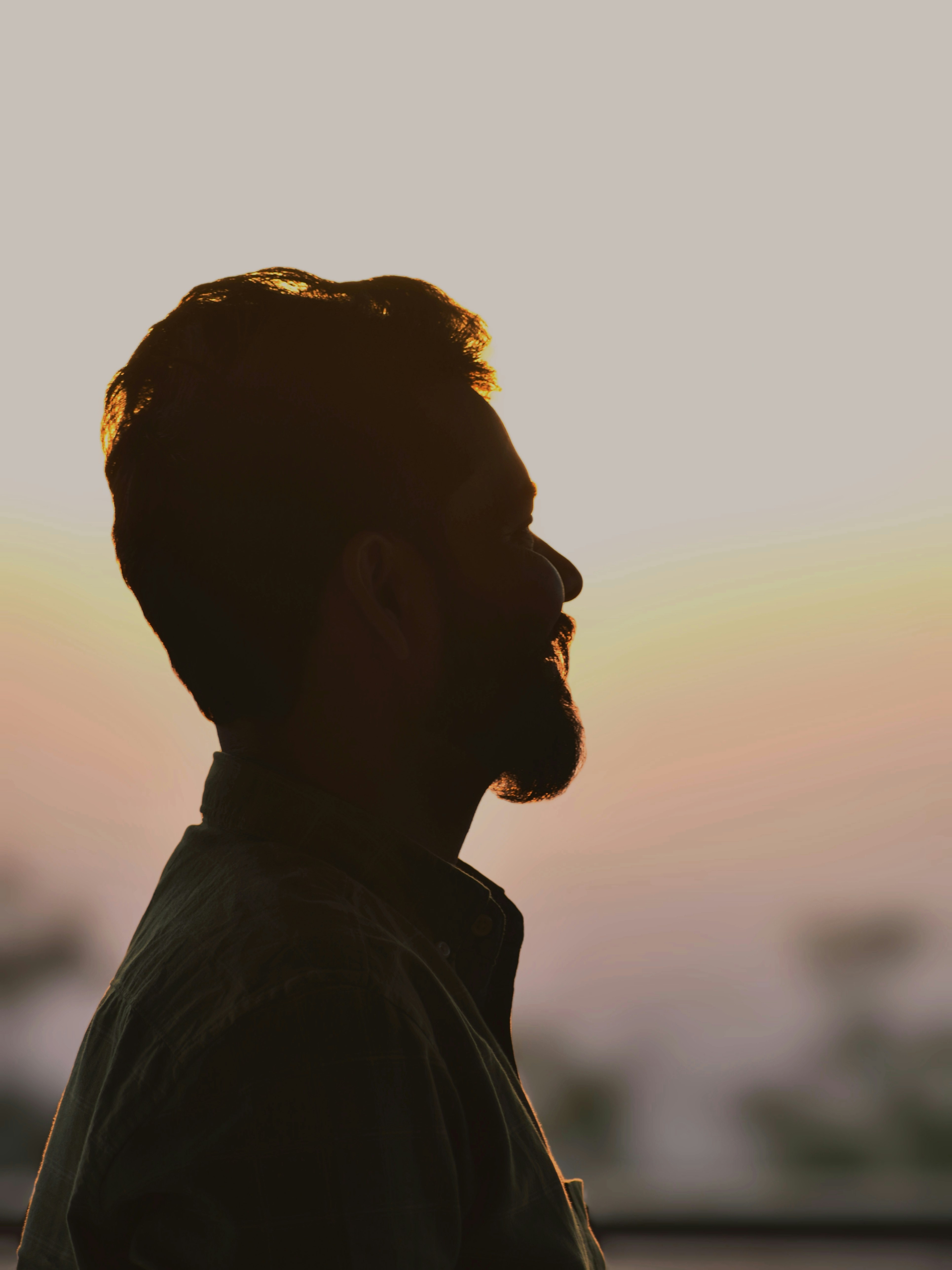 A silhouetted profile of a man against a soft sunset background, showcasing a peaceful expression.