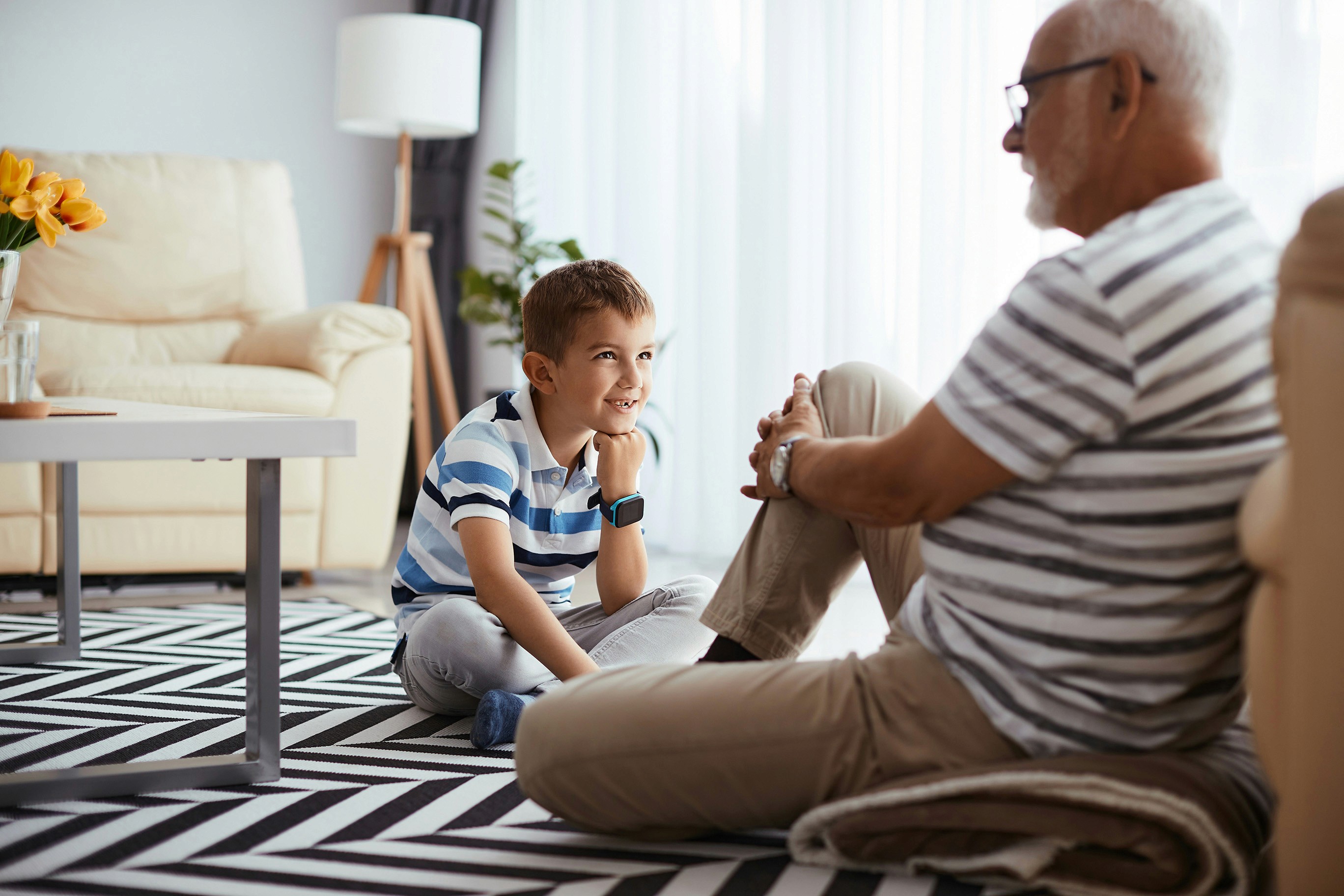 A grandfather sitting wityh his grandson on the living room floor