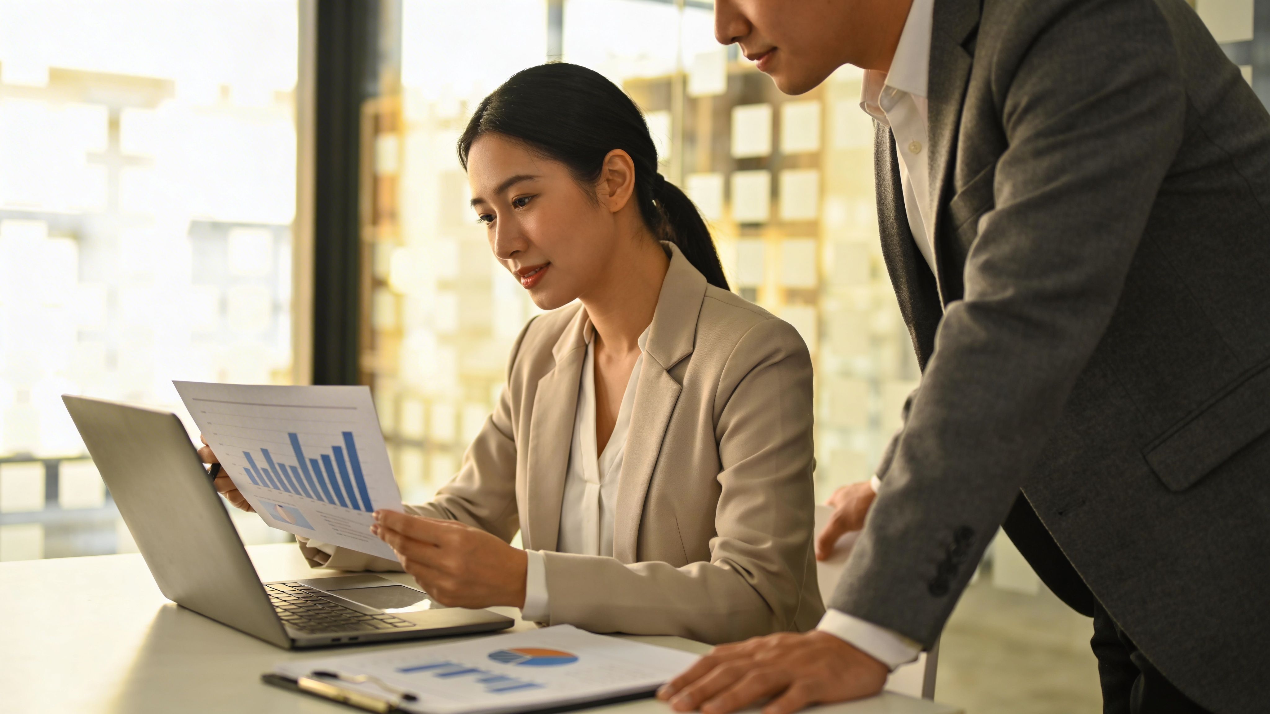 Professionals analyzing financial charts on a laptop in a modern office workspace