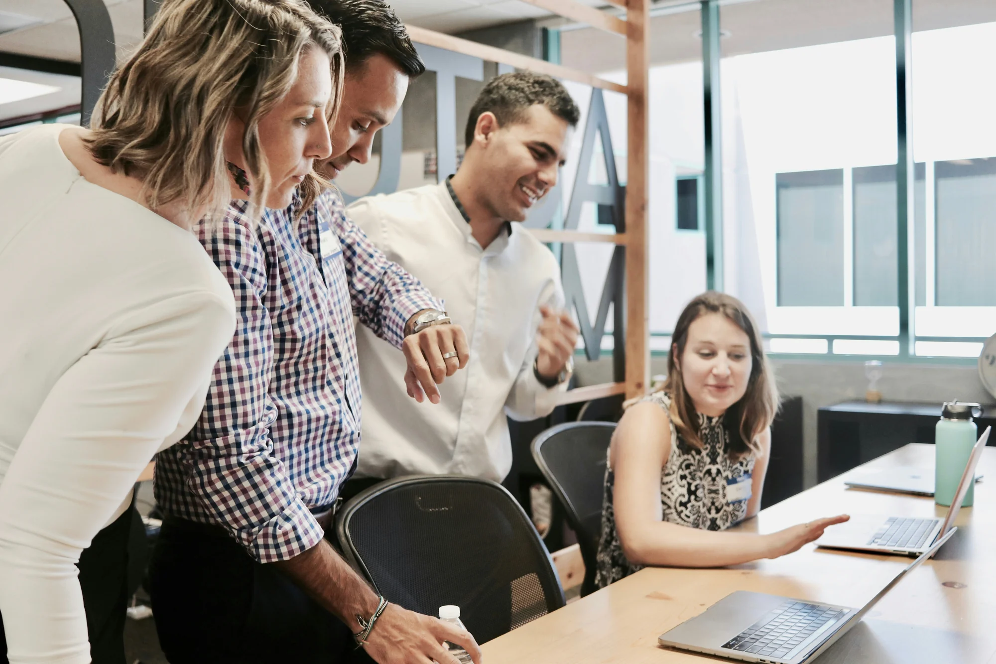 Colleagues reviewing laptop screen together in bright office workspace