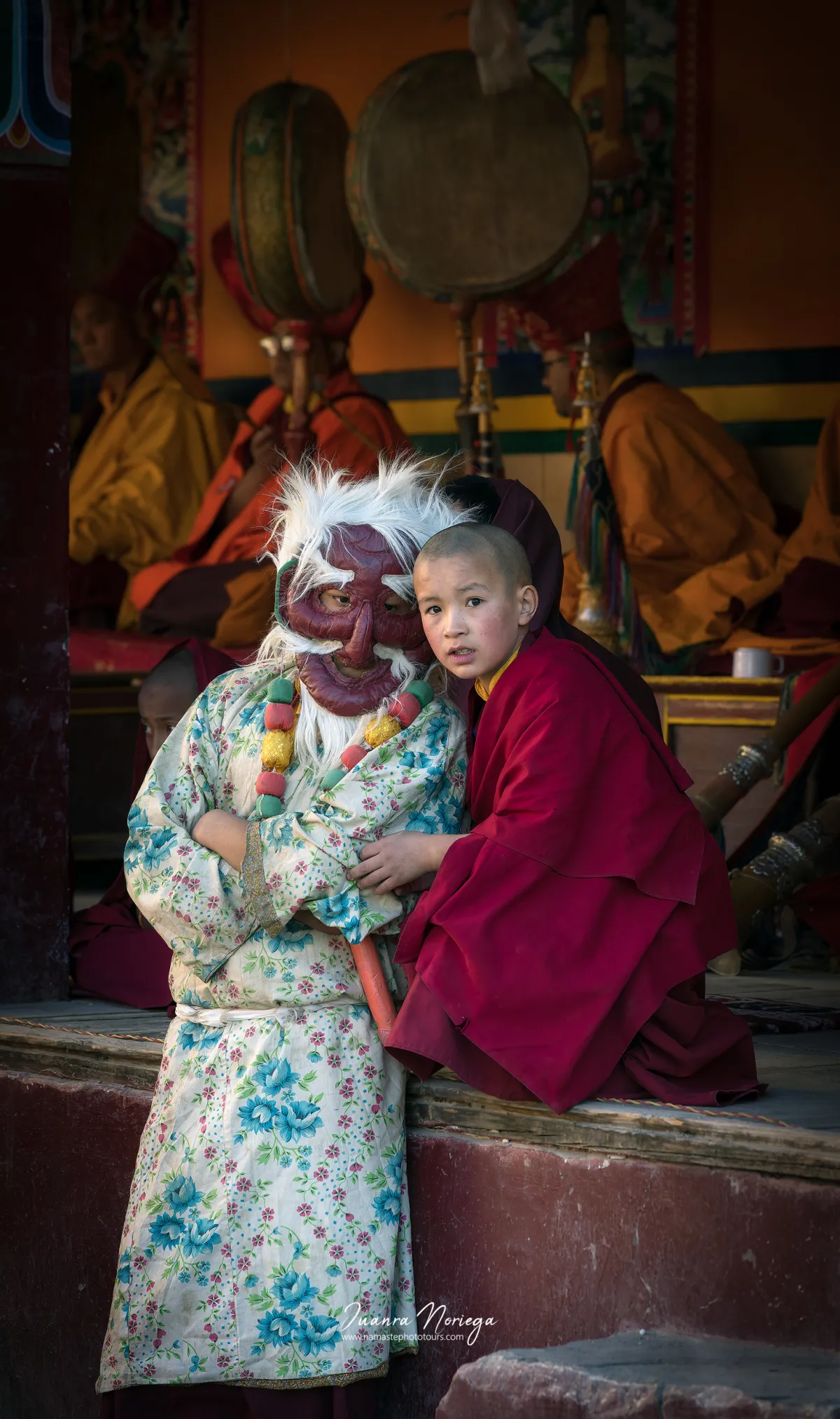 Niño monje abrazado a un personaje enmascarado durante un festival cham en Ladakh