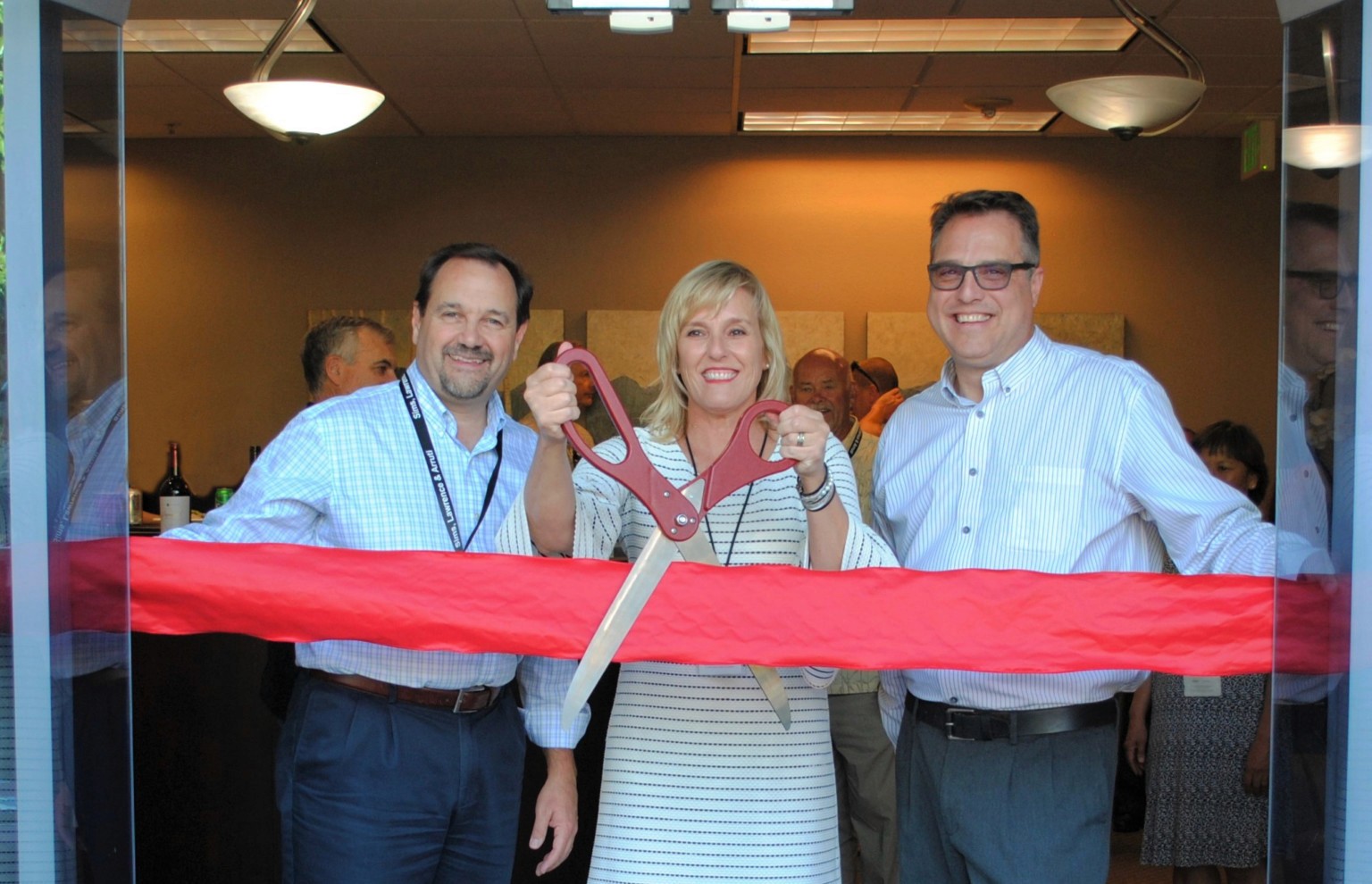 Sims, Lawrence & Broghammer cutting a red ribbon on opening day of their new headquarters.