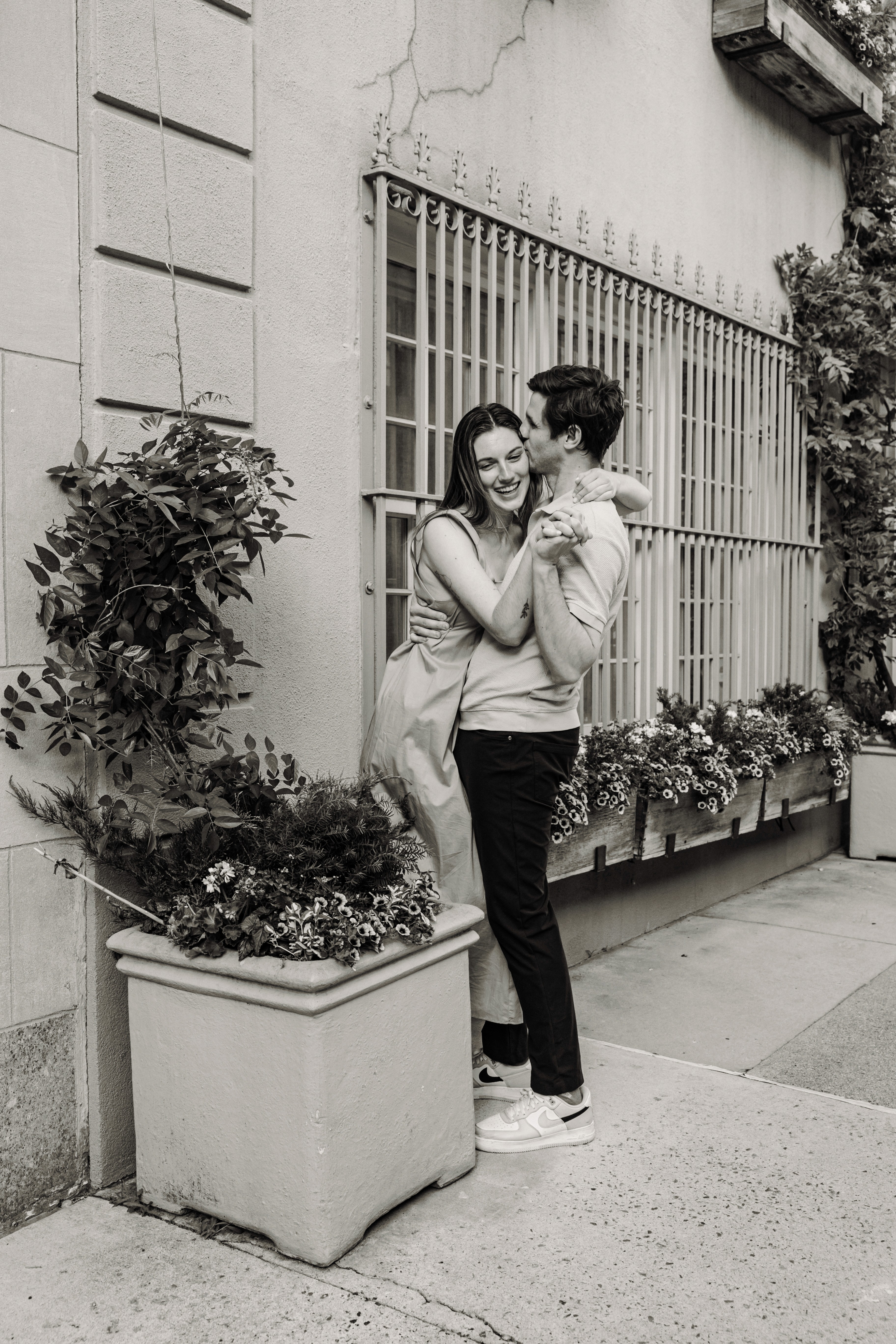 Family of five in a candid, joyful moment at the Hall of Springs in Saratoga Springs, NY — dad gazing at mom, baby in her arms, while their son and daughter come running toward the camera — natural family photography by Lizz Spano Photography, Saratoga Springs family photographer.