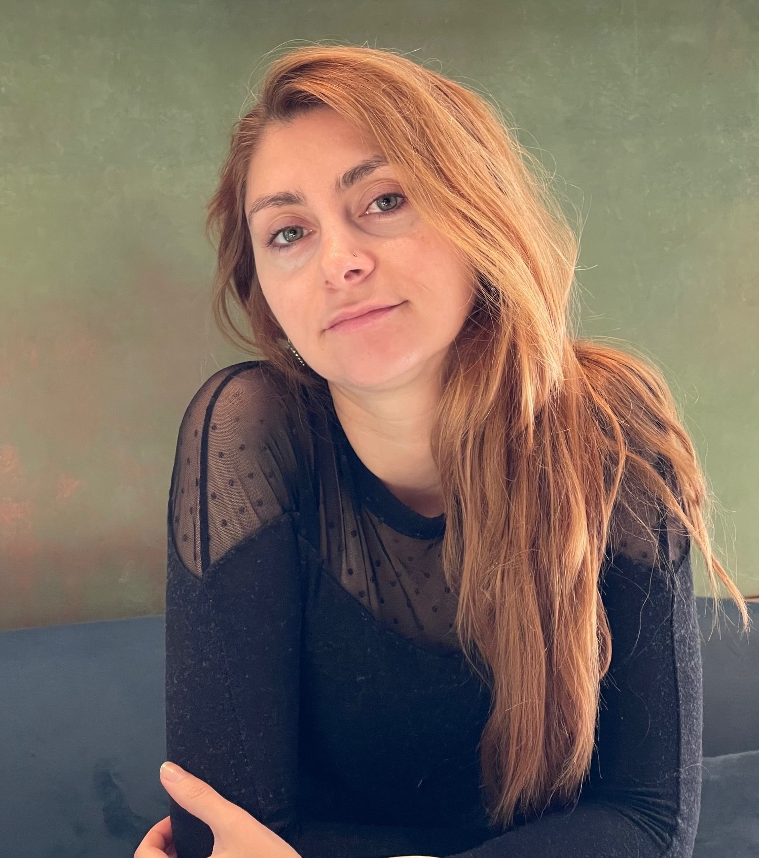 Porträtfoto einer Frau Mitte 30 mit langen braunen Haaren in einem schwarzen Oberteil