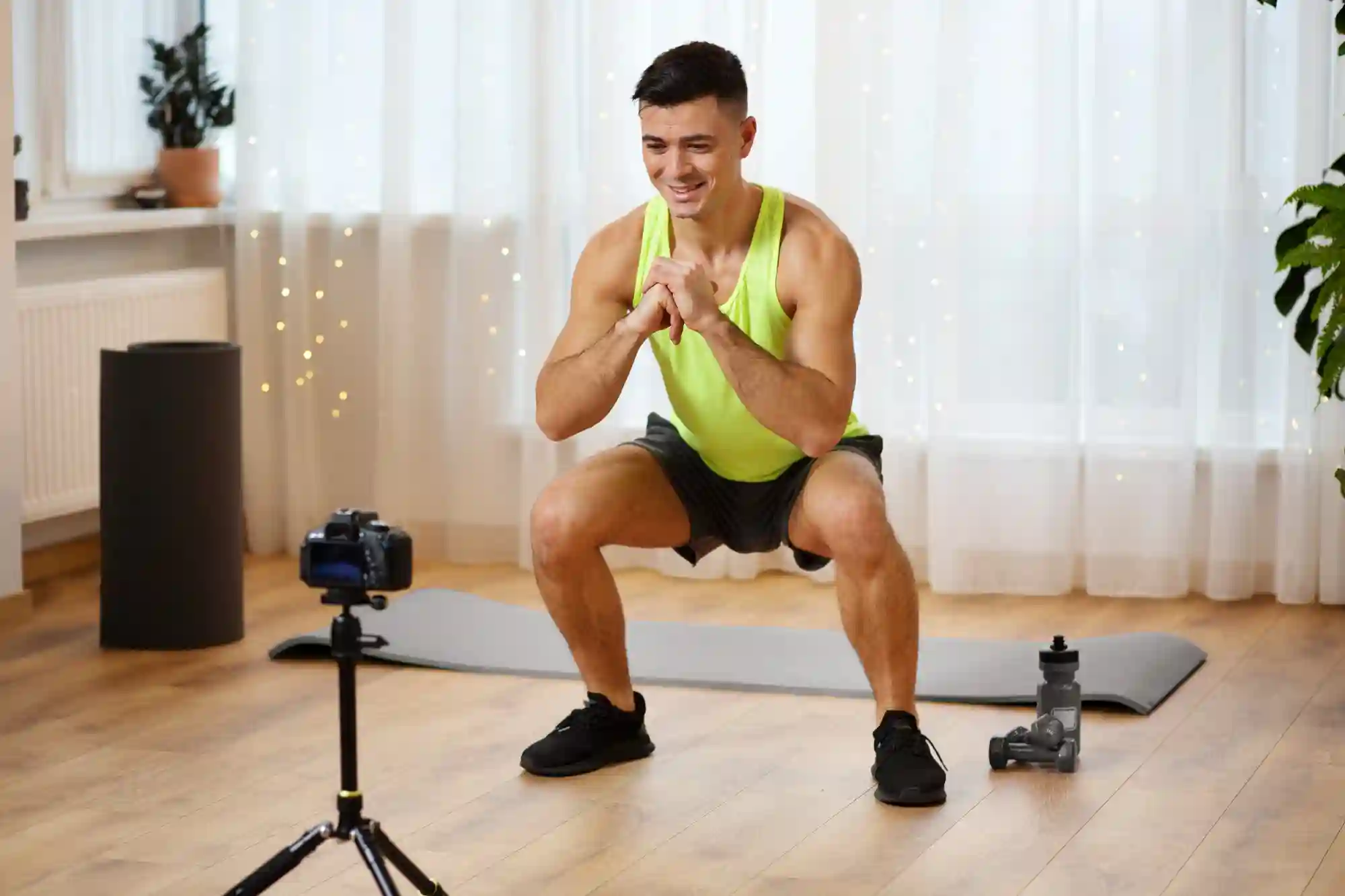 A fitness blogger recording a squat tutorial at home on a camera for his online workout audience.