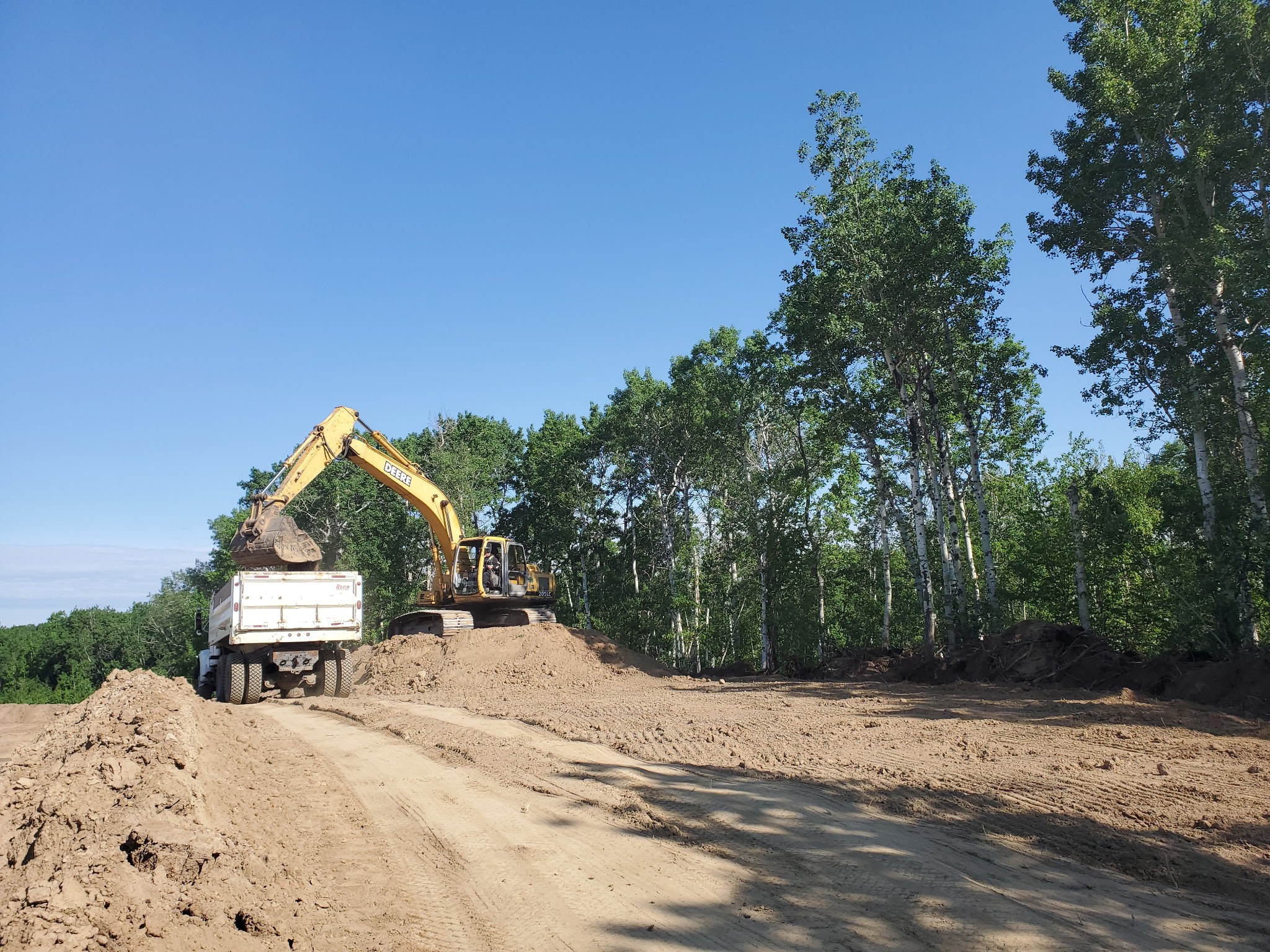 a excavator sitting on a pile loading a gravel truck