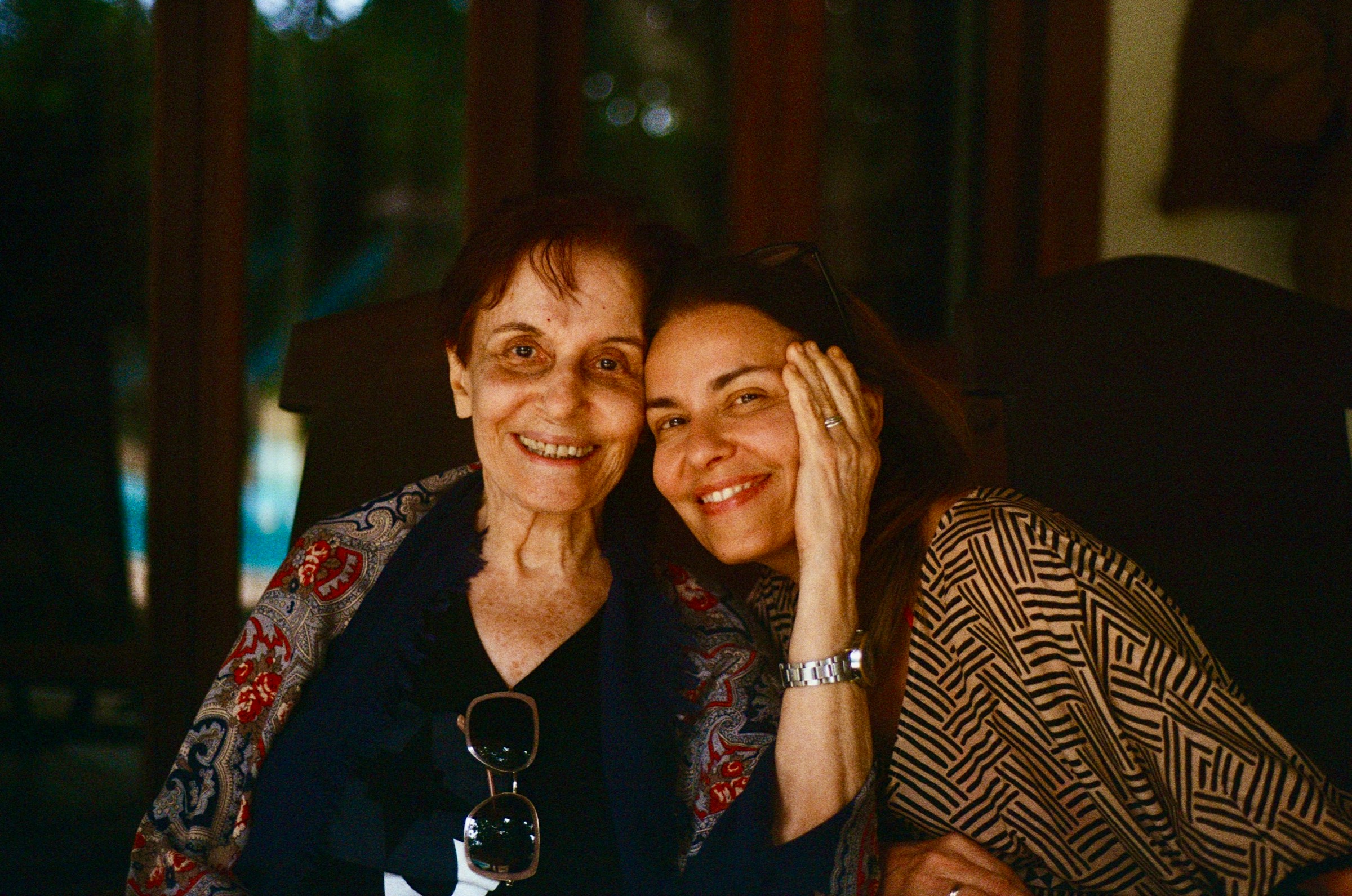 An adult daughter and her mother smiling together at home