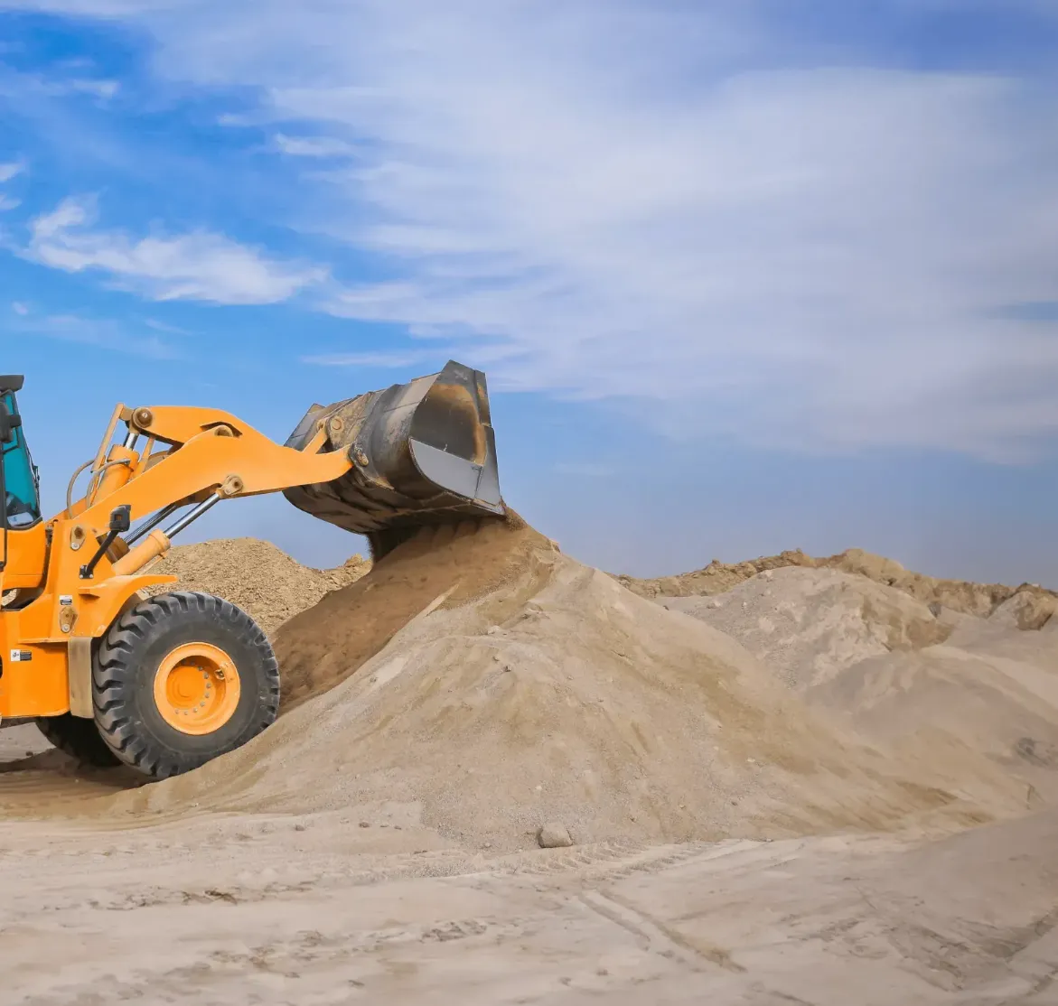 A loader dumping sand into a pile