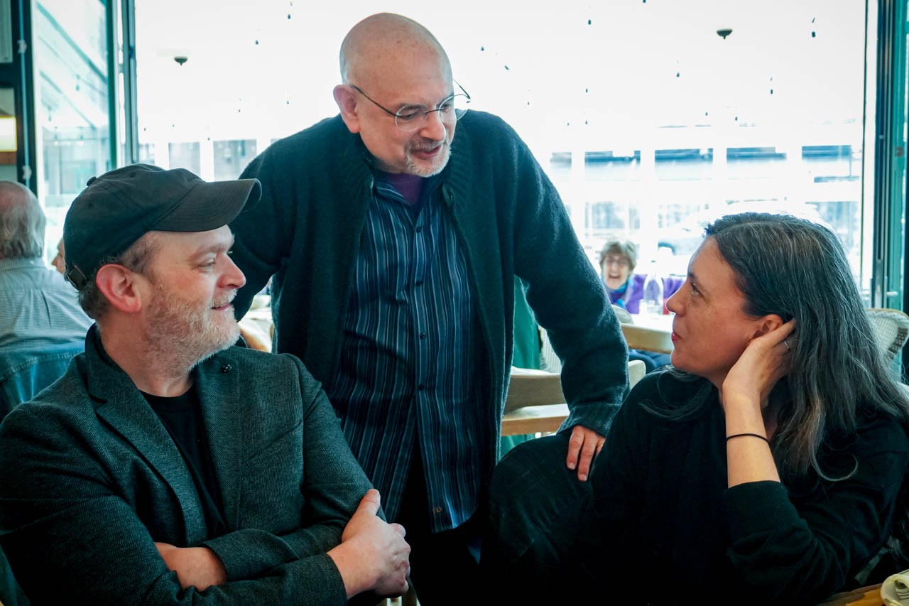 three people talking at a table in a restaurant