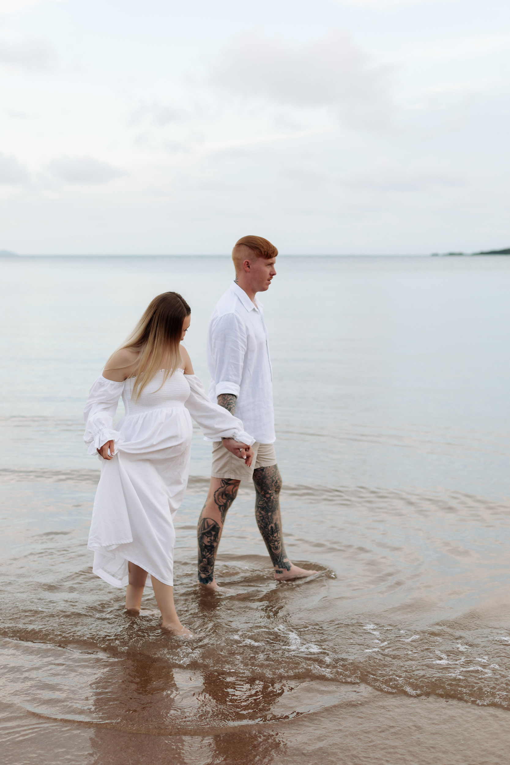 Expecting couple walking along the beach at sunset in Mackay during a maternity photography session