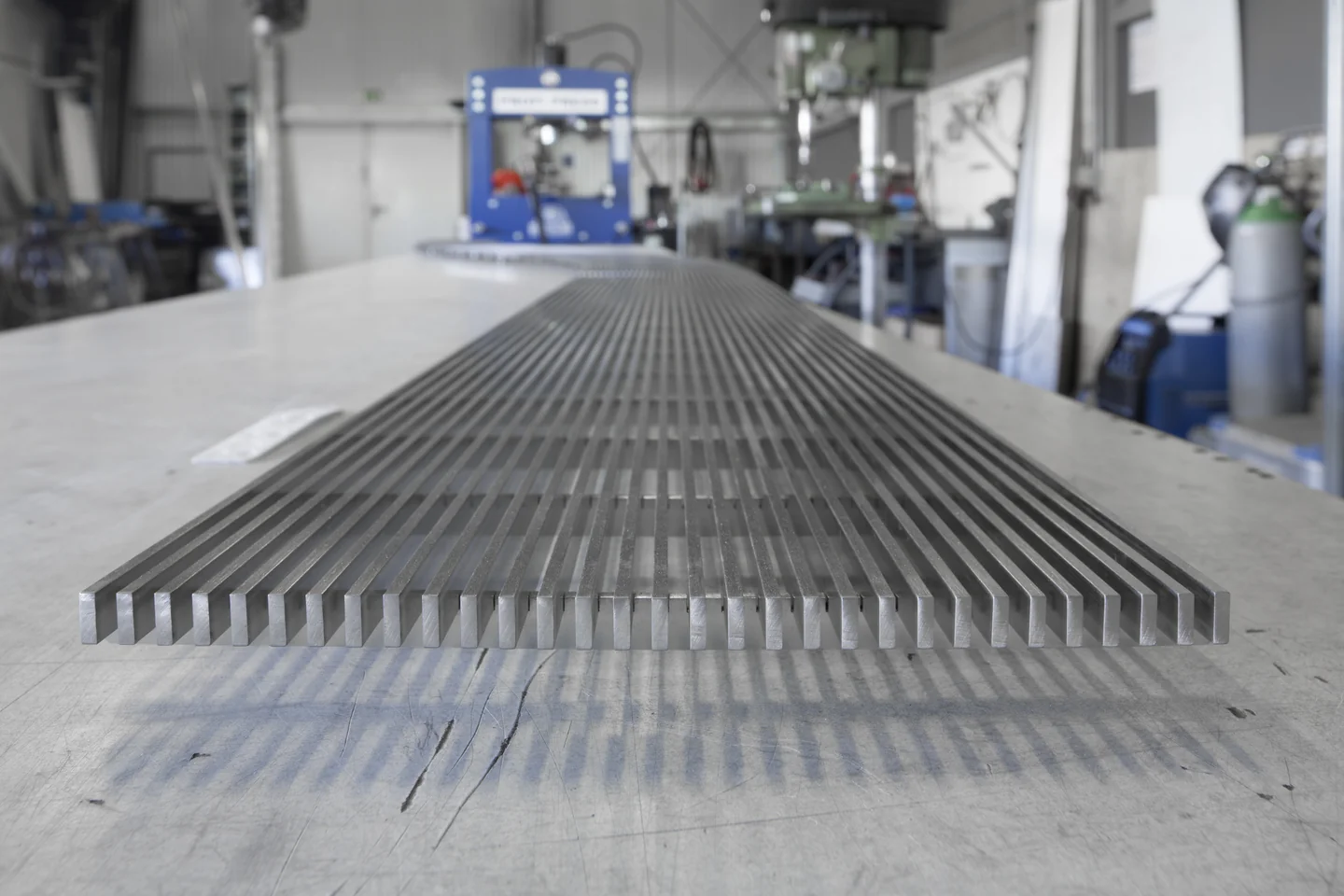 Parallel angeordnete Metallprofile auf einem Werkstatttisch bei PORTEC.