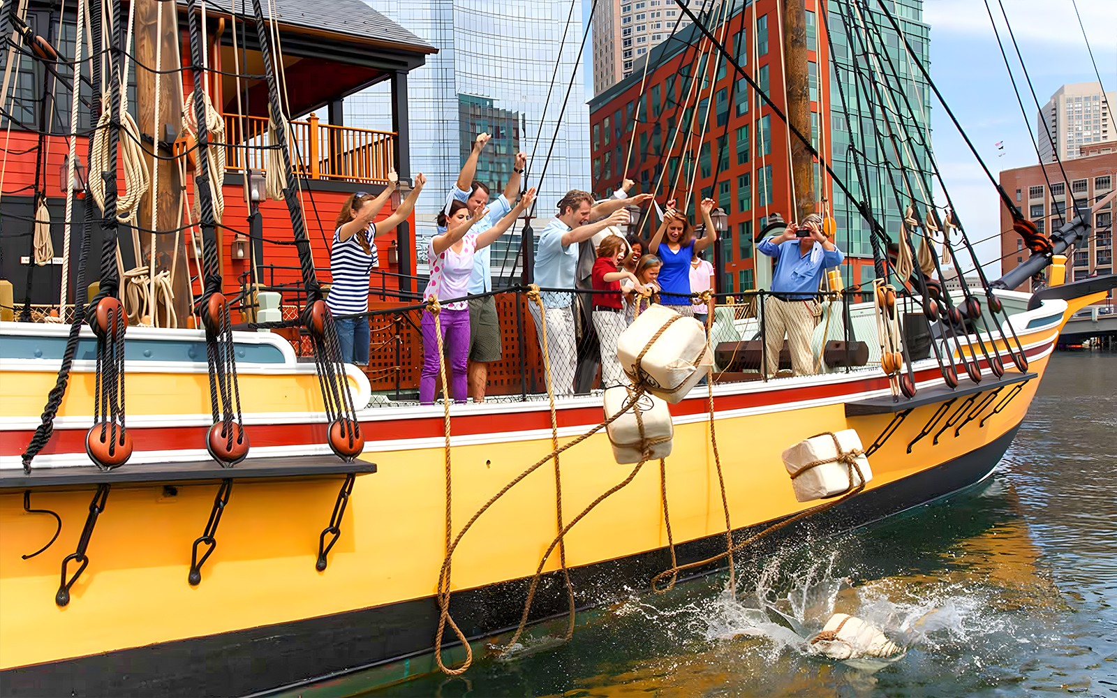 Tourists reenacting the Boston Tea Party by throwing tea chests from a ship in Boston Harbor.