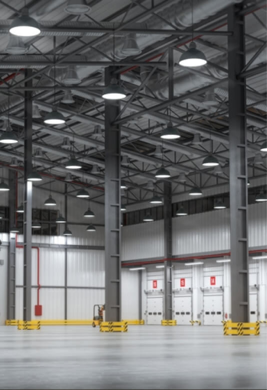 A spacious warehouse interior featuring tall ceilings and metal beams, with bright overhead lights.