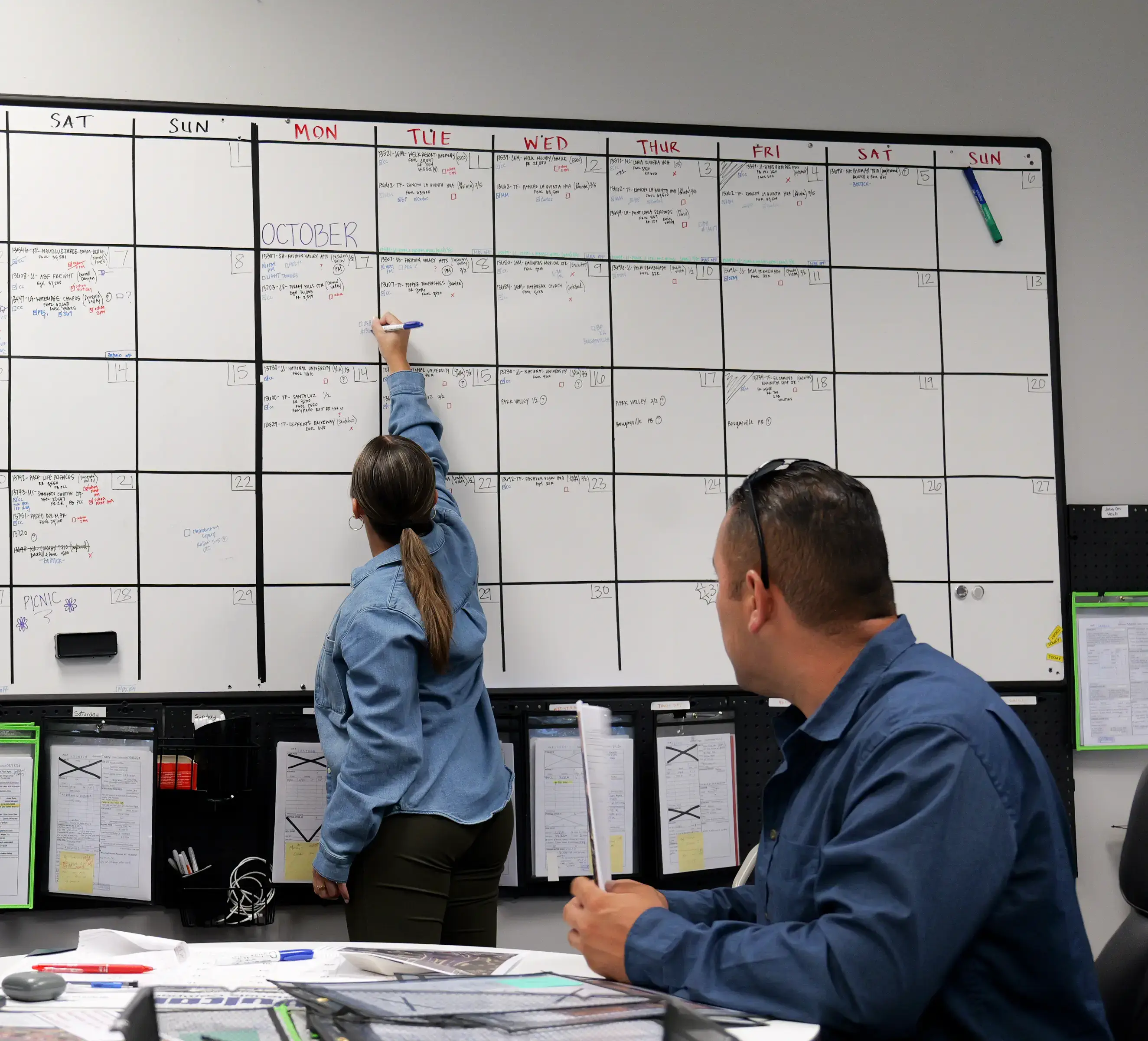 Office managers adding projects to whiteboard projects schedule