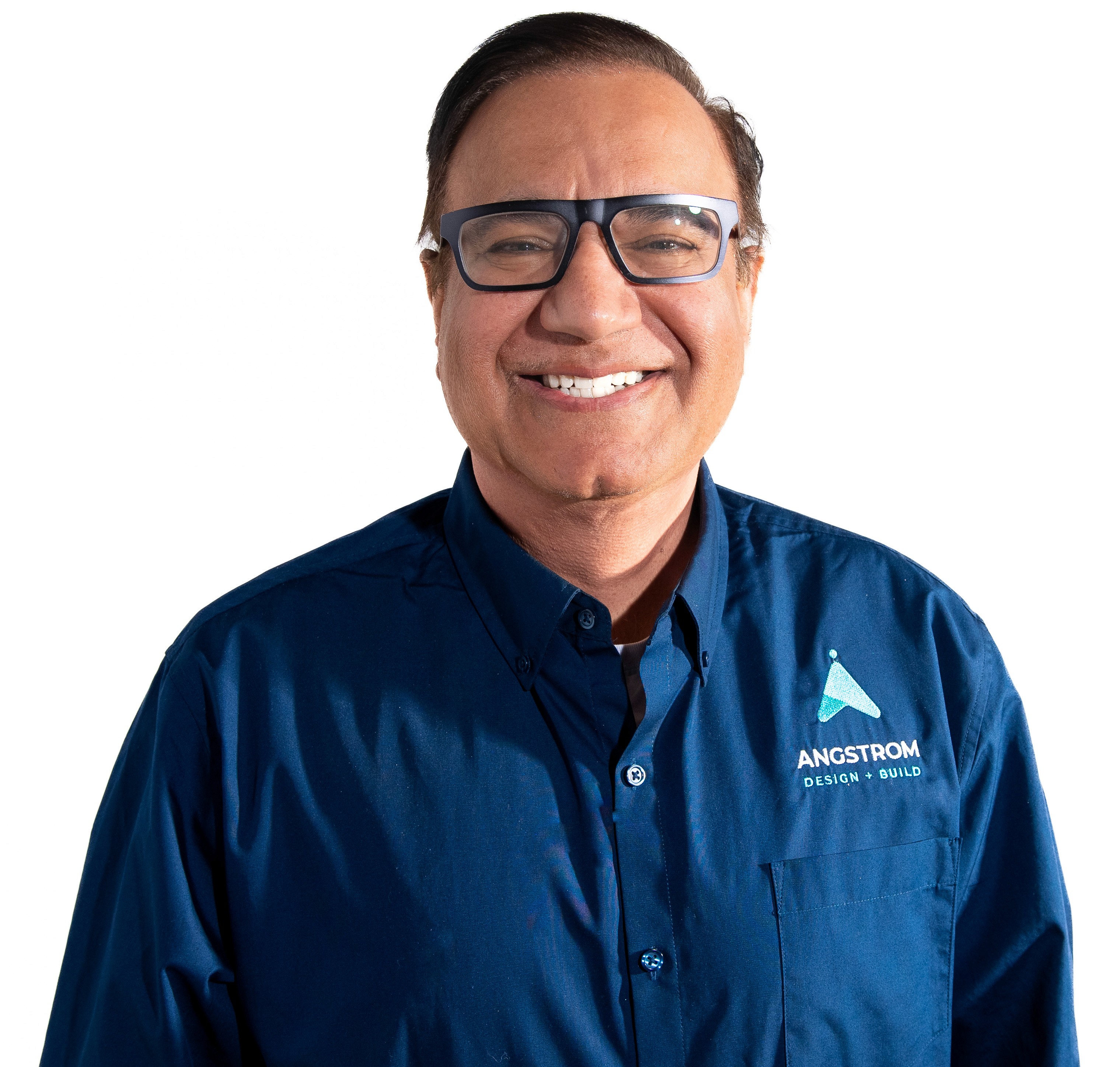 Smiling young woman with curly hair sitting at a laptop, in front of a teal wall.