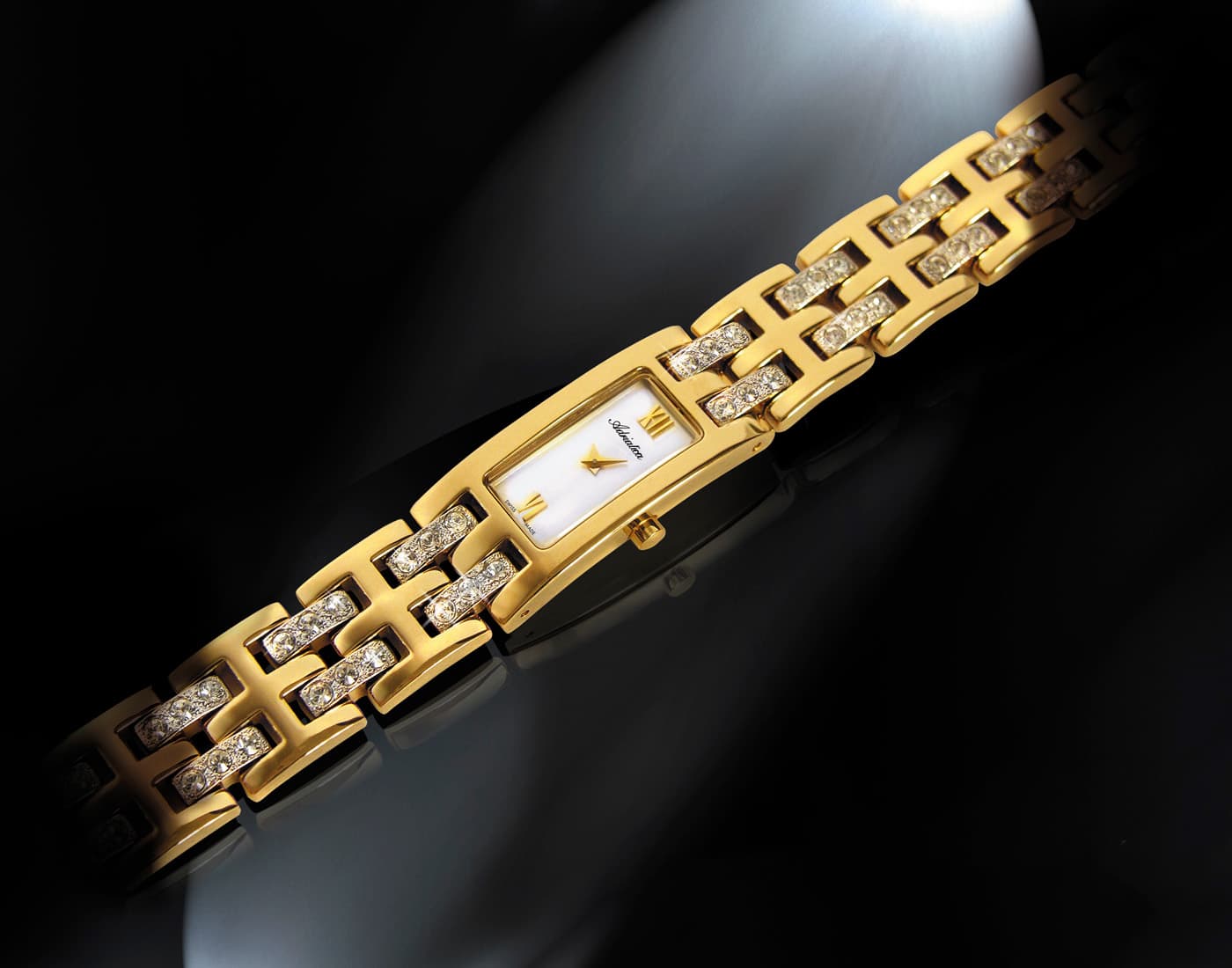 Luxury gold bracelet watch with diamond-set links and rectangular white dial, photographed on a dark reflective background.