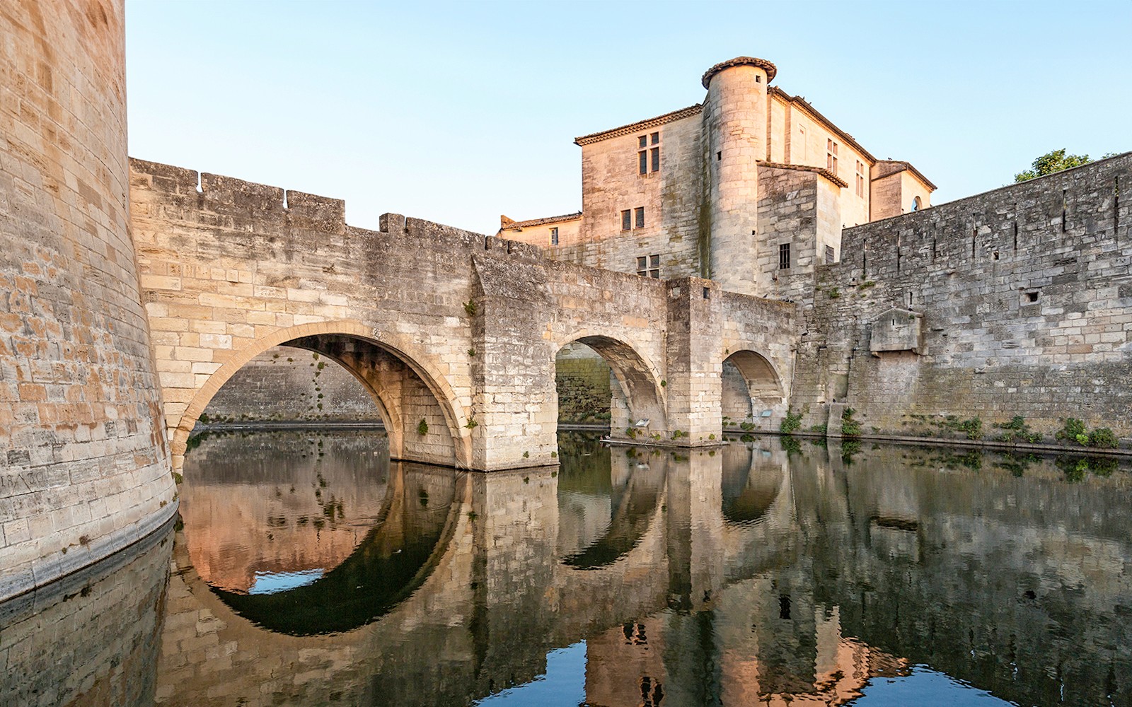 Towers and ramparts of Aigues-Mortes reflected in water, France.