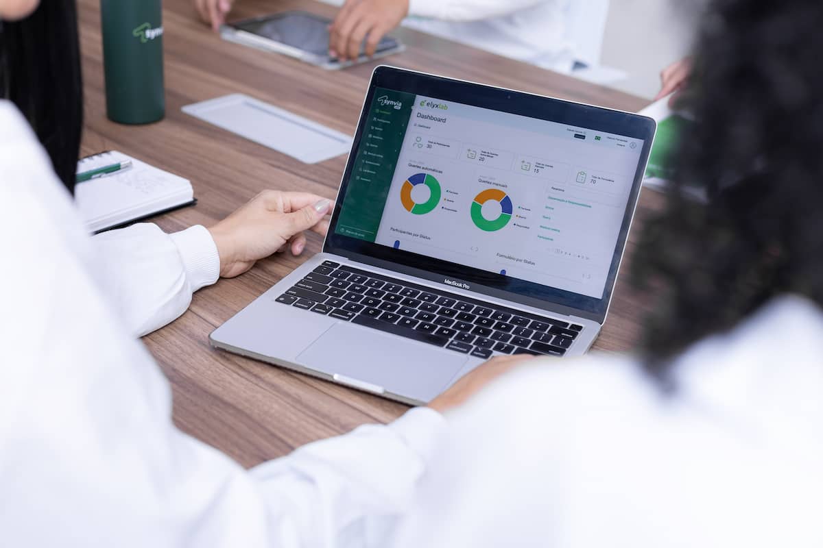 Equipe da Synvia realizando planejamento estratégico para estudos clínicos com análise de dados em dashboard