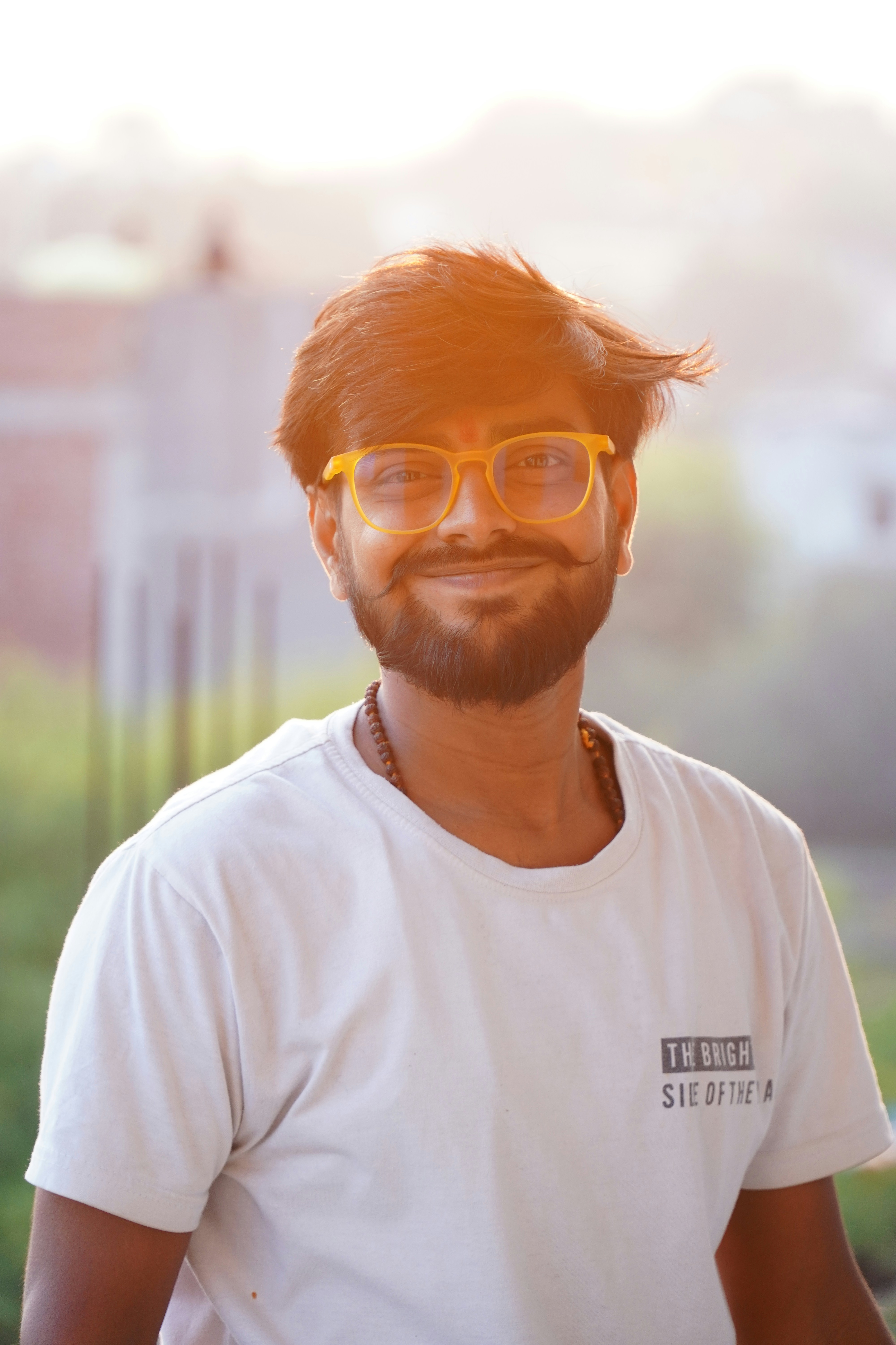 A man with a beard wearing glasses and a white t - shirt