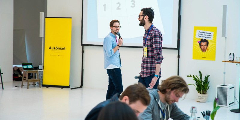 Two workshop facilitators giving exercise instructions to a room full of people