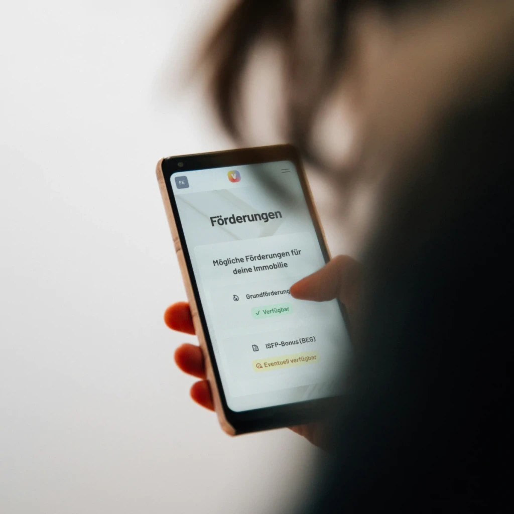 Mensch mit Smartphone in der Hand Bildschrim zeigt Übersicht von Fördermitteln