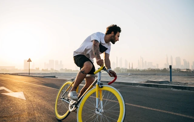 Cyclist riding on a road with a city skyline in the distance